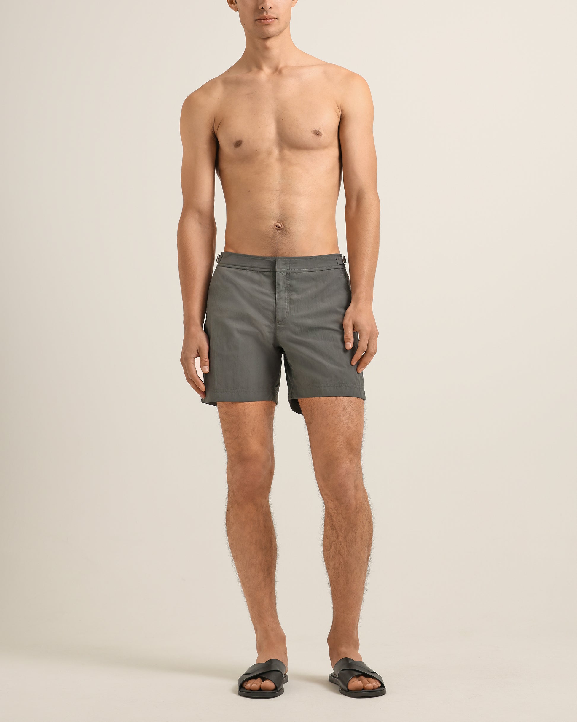 Man wearing gray swim shorts on a beige background