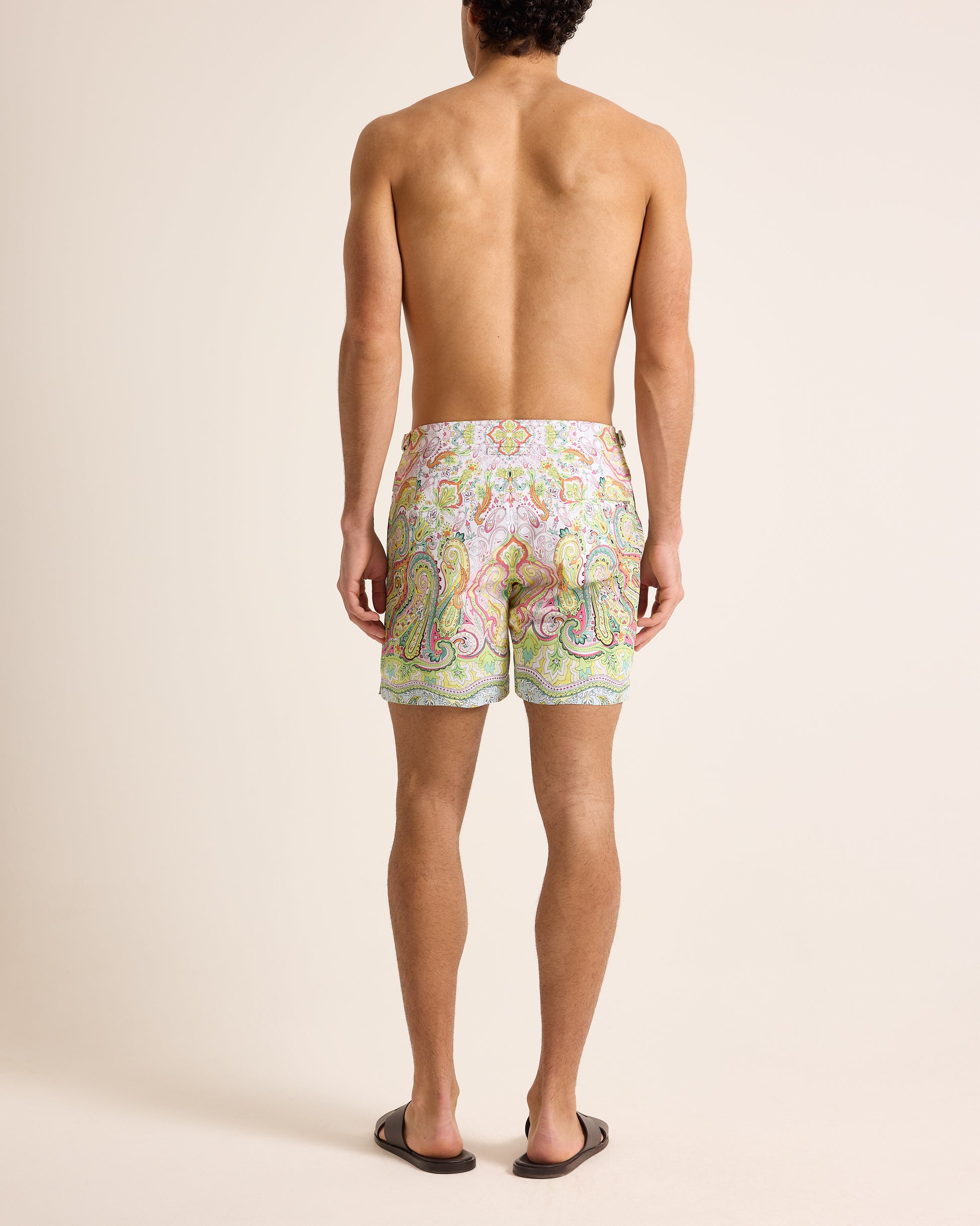 Person wearing multicolour print swim shorts on a plain background