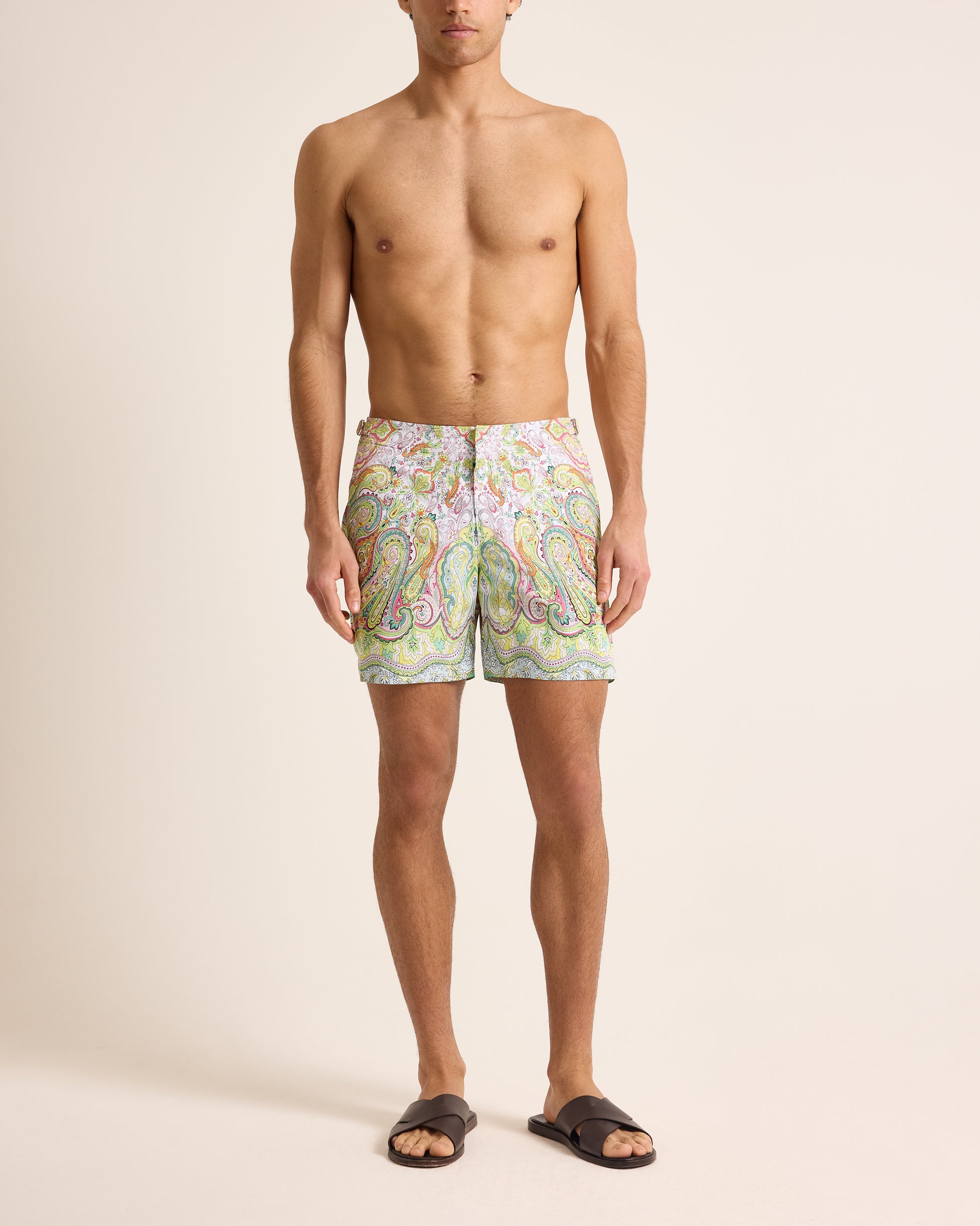 Man wearing colorful patterned swim shorts on a beige background