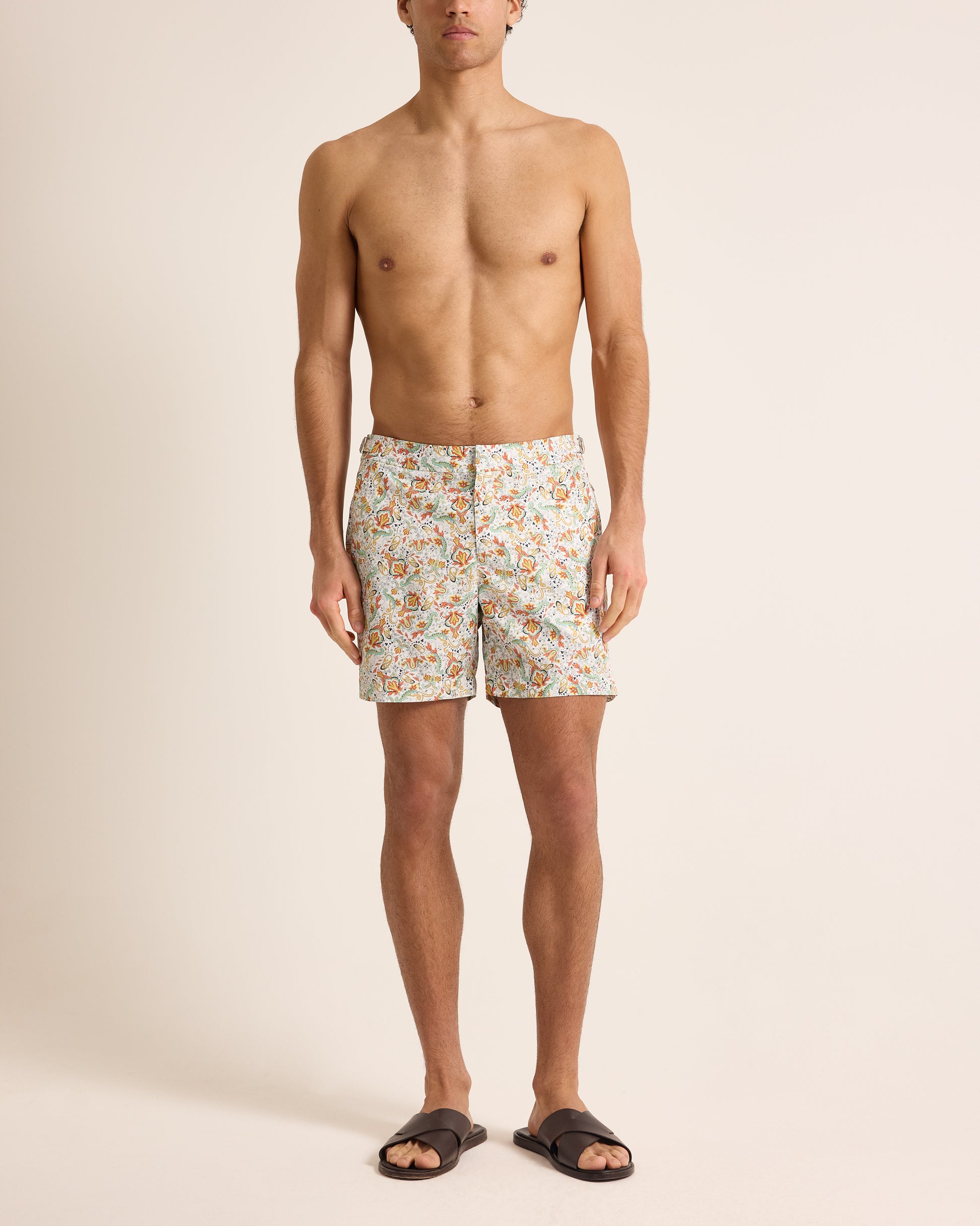 Man wearing floral swim shorts on a beige background