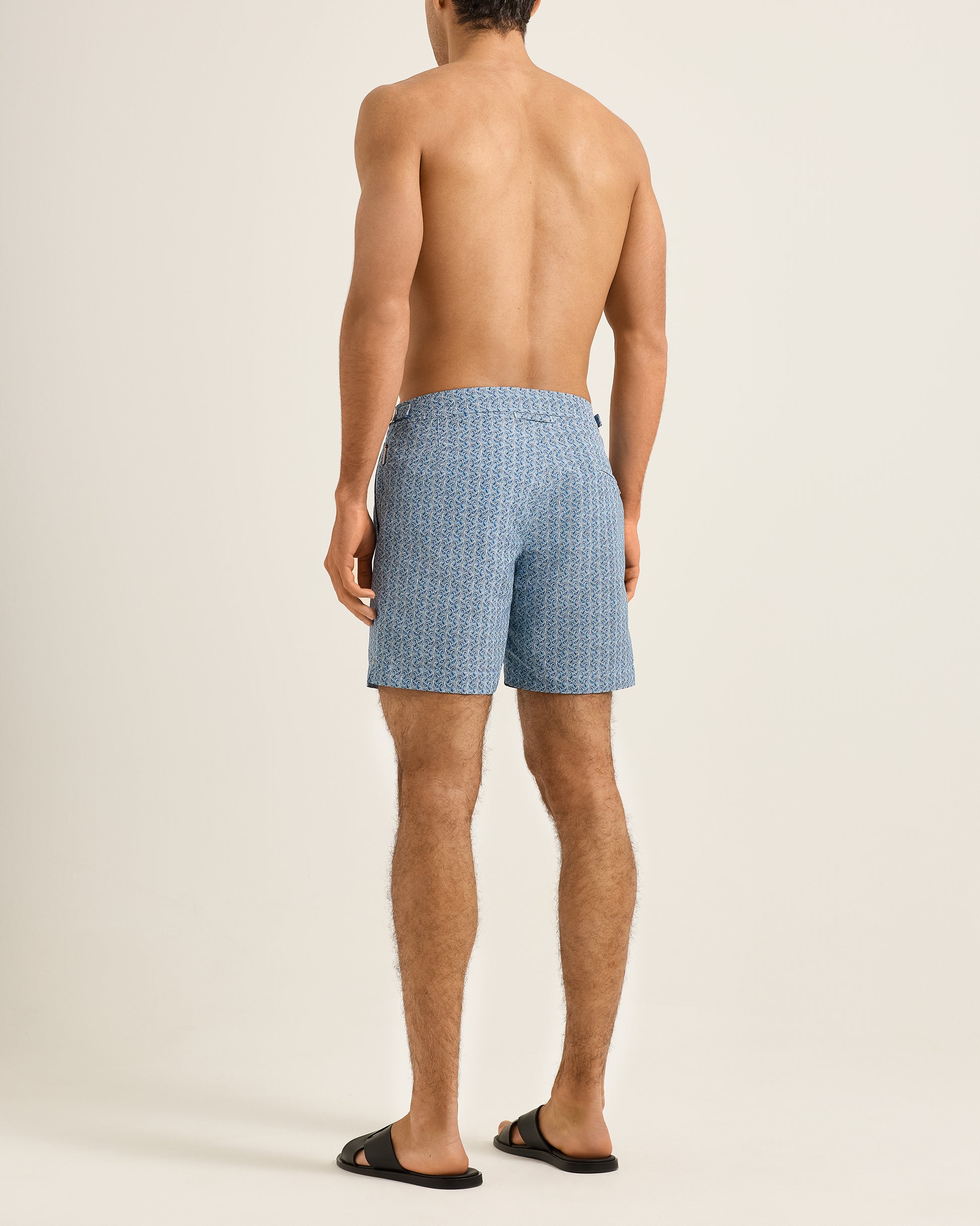Man wearing blue patterned swim shorts on a beige background