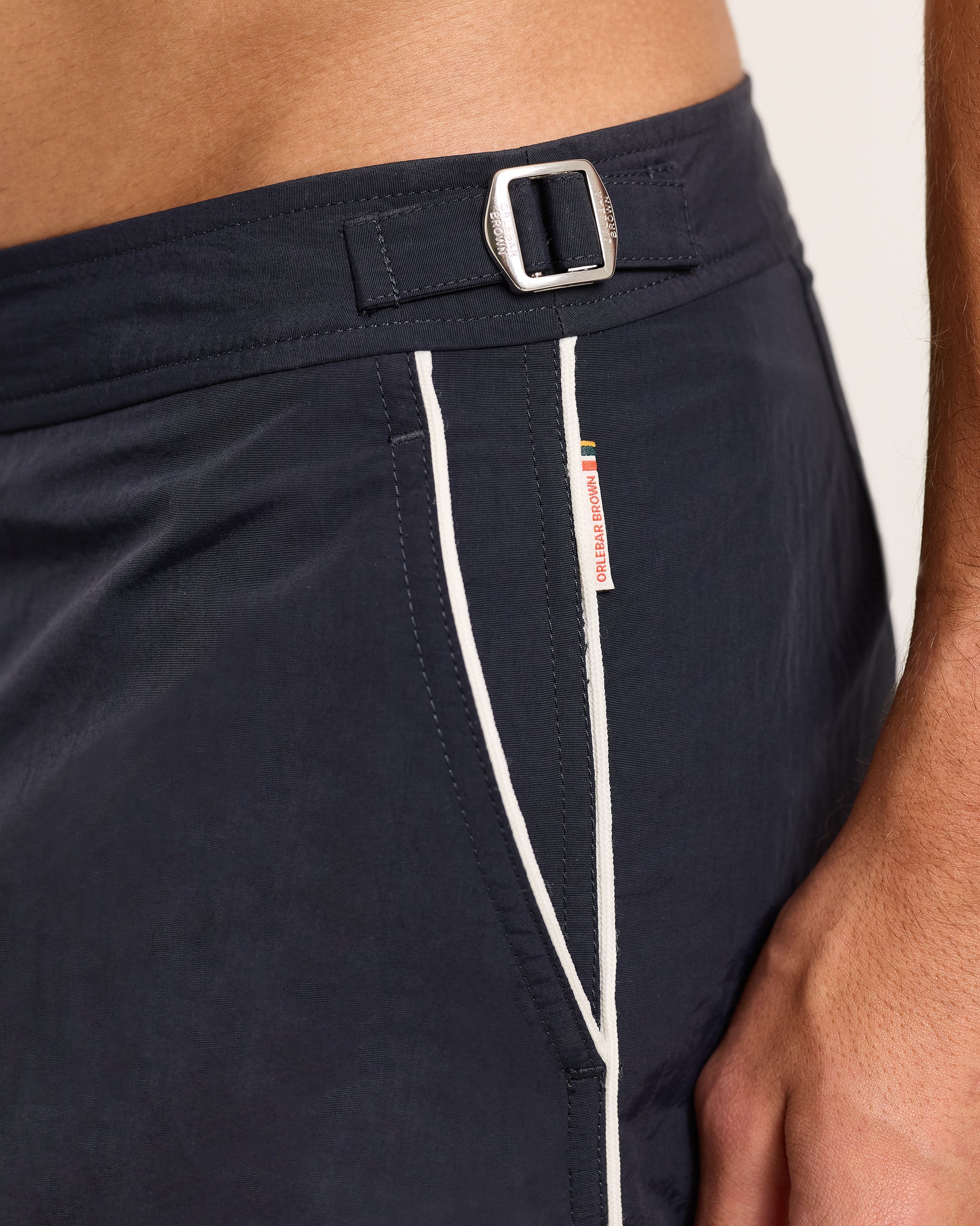 Navy shorts with a white stripe and brand tag on a neutral background