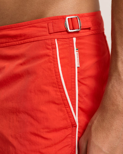 Close-up of red shorts with a silver buckle on a neutral background