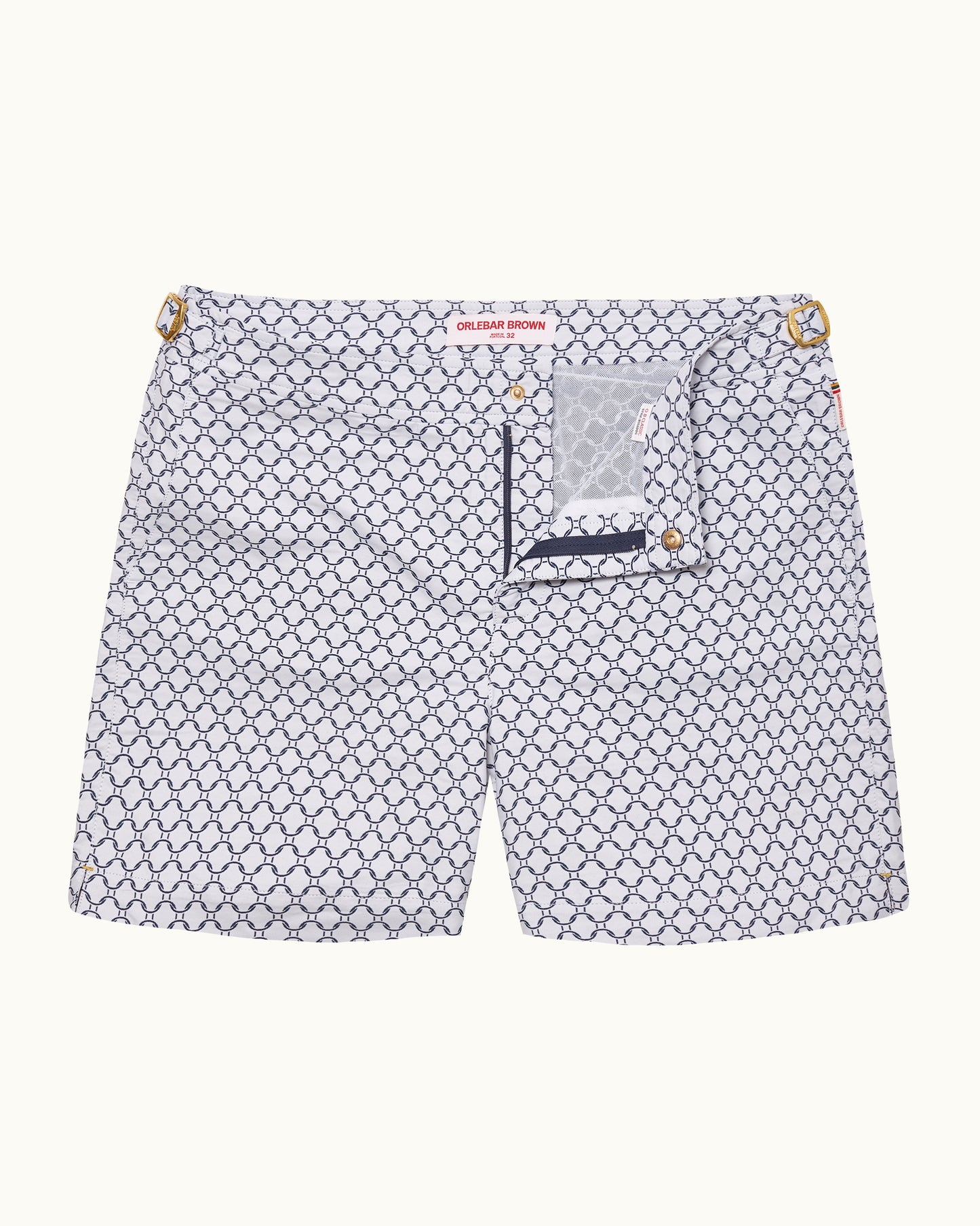 A pair ofchino shorts by Gucci featuring a white base with a navy blue repeating geometric monogram pattern, gold-tone metal hardware at the waist, and a small branded patch on the back pocket.