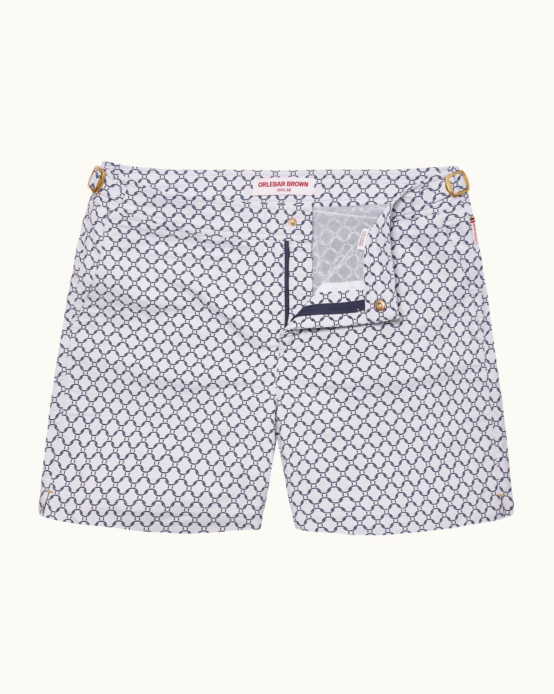 A pair ofchino shorts by Gucci featuring a white base with a navy blue repeating geometric monogram pattern, gold-tone metal hardware at the waist, and a small branded patch on the back pocket.