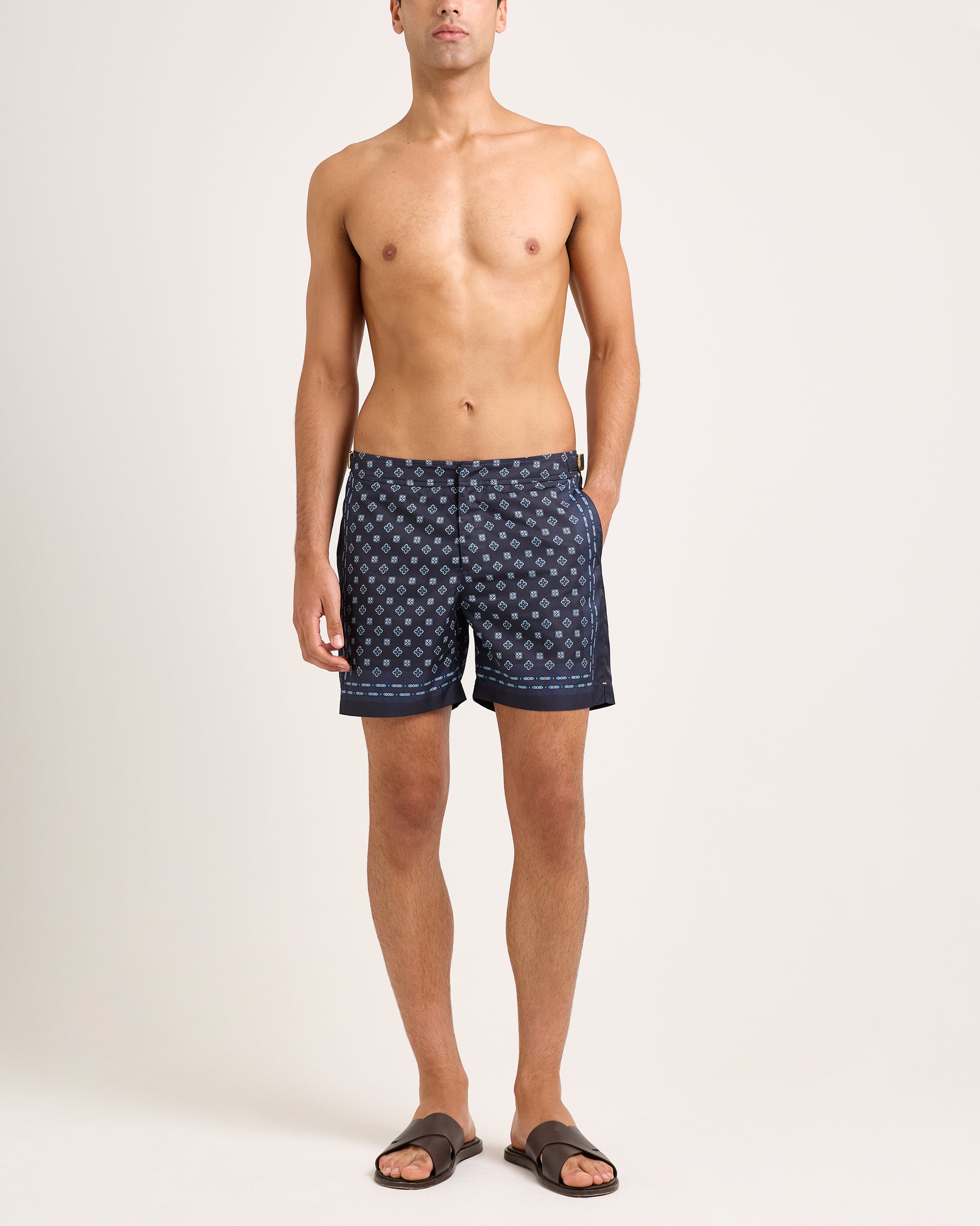 Man wearing navy swim short with geometric pattern on light background