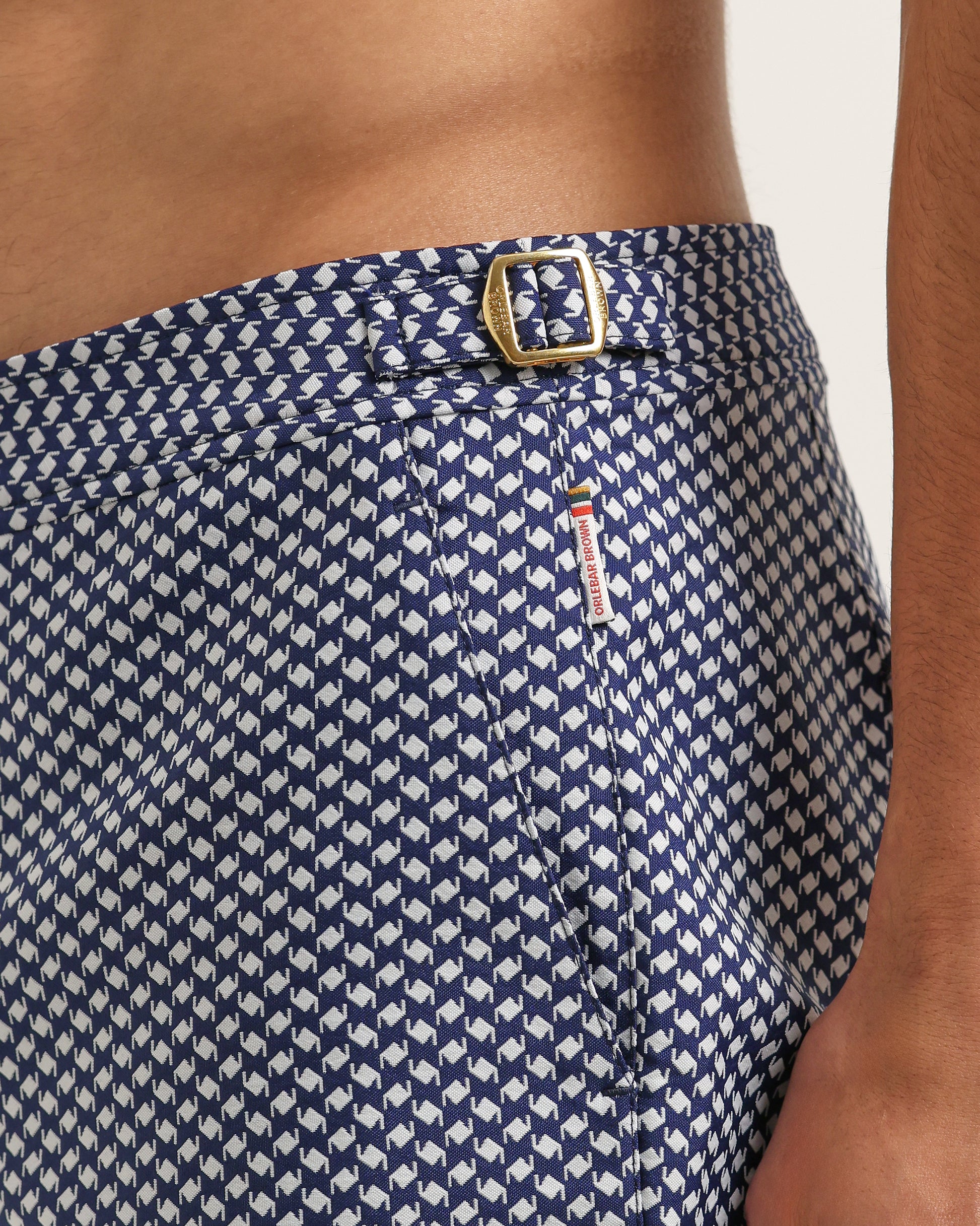 Navy blue shorts with white pattern and gold buckle on a neutral background