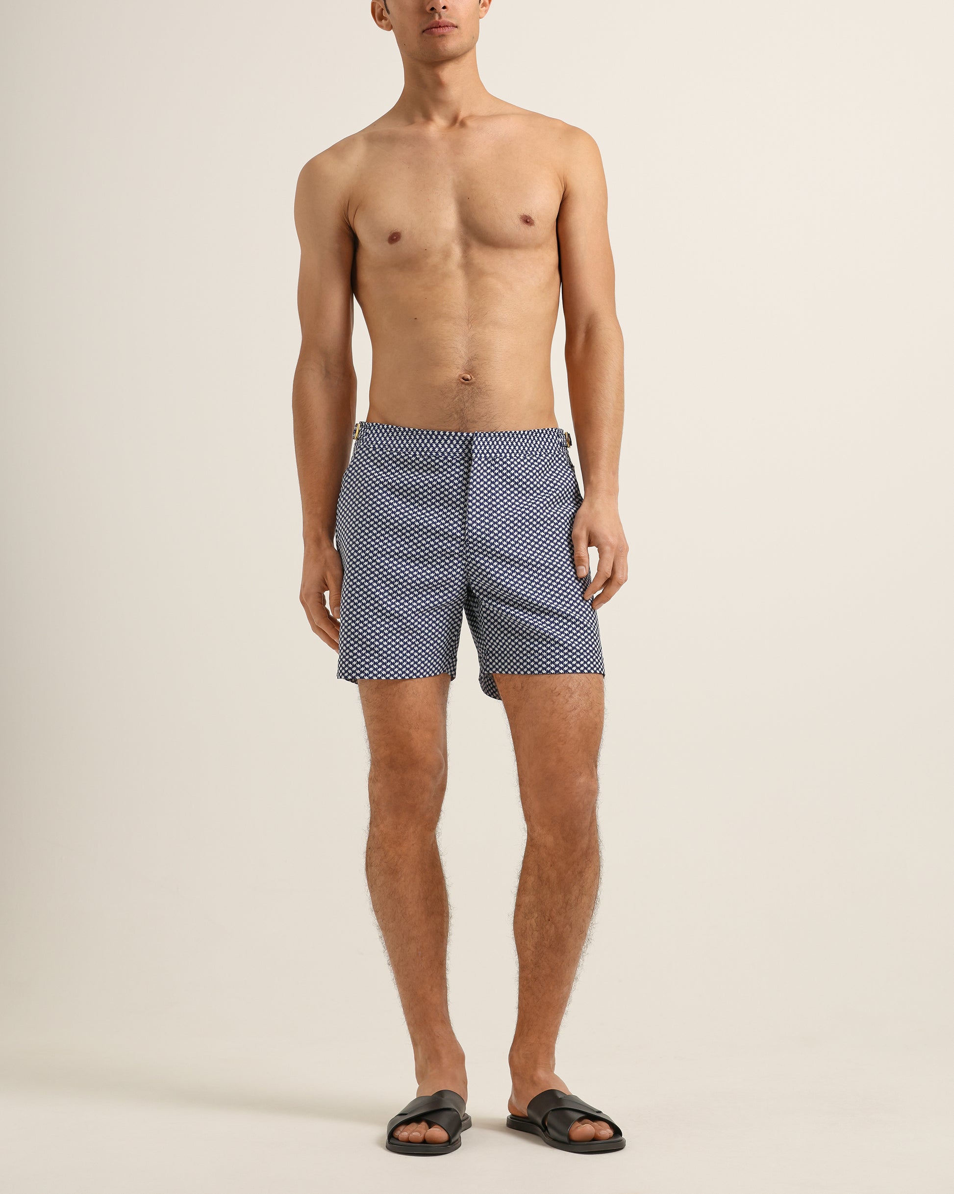 Man wearing blue patterned swim shorts on a beige background