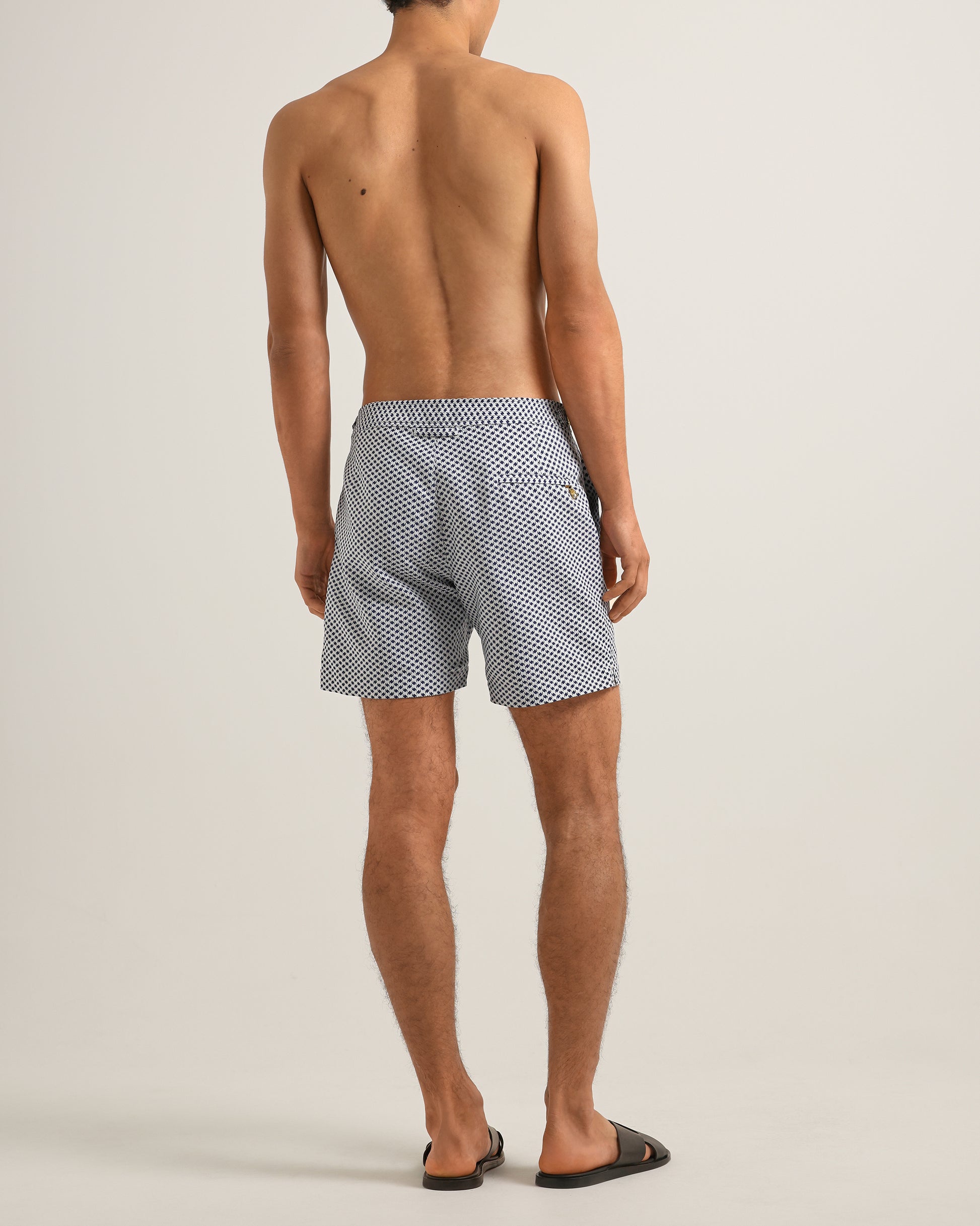Person wearing patterned swim shorts on a plain background