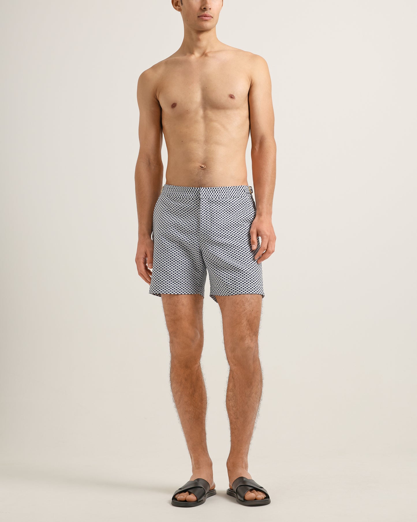 Man wearing black and white checkered swim shorts on a beige background
