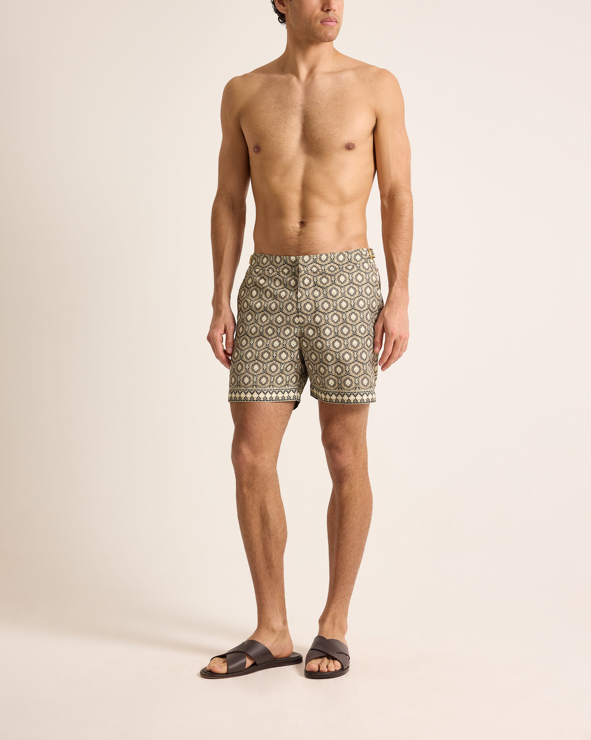 Man wearing patterned swim shorts on a beige background