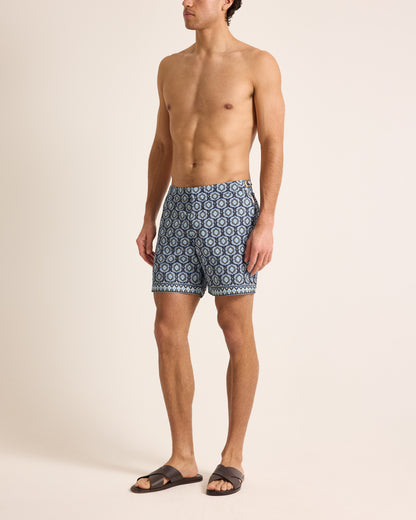 Man wearing blue patterned swim shorts on a beige background