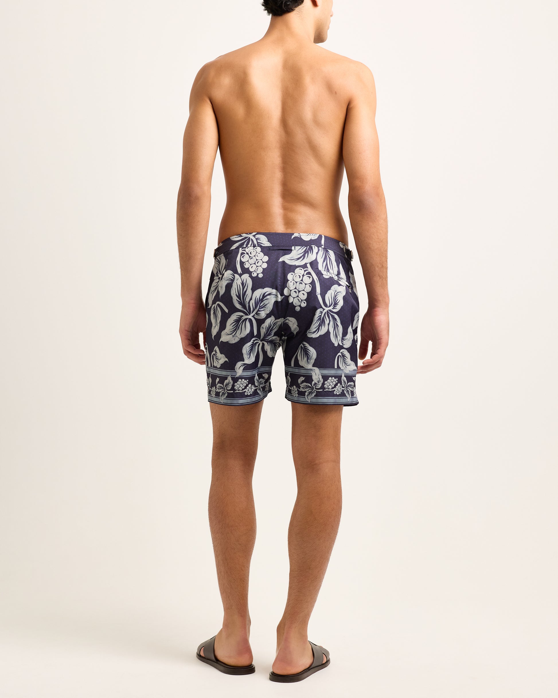 Man wearing navy floral swim shorts on a white background