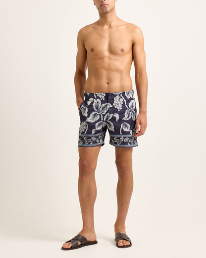 Man wearing navy floral swim shorts on a white background