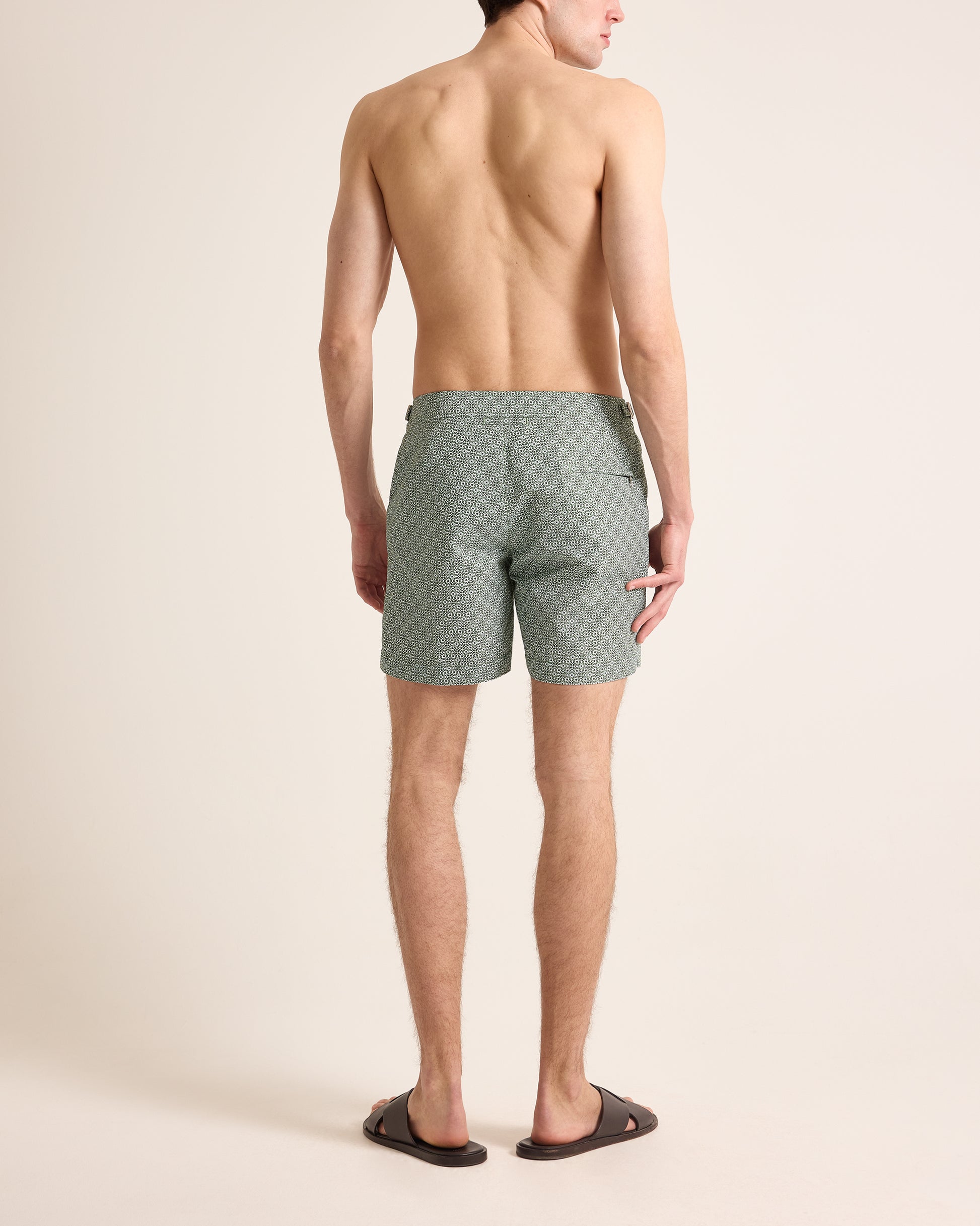 Man wearing green patterned shorts on a beige background
