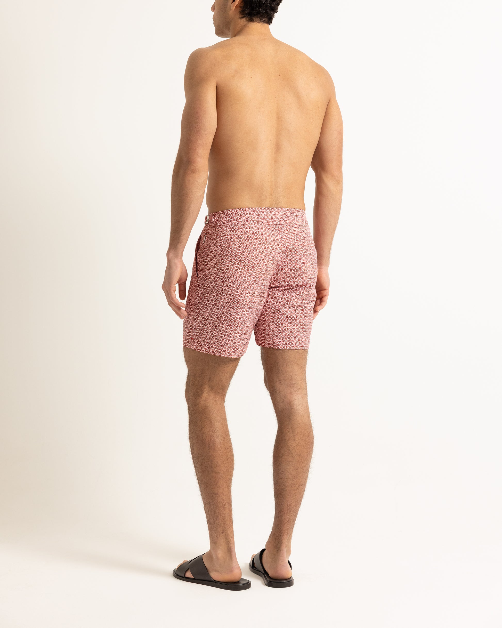 Man wearing red printed swim shorts on a plain background