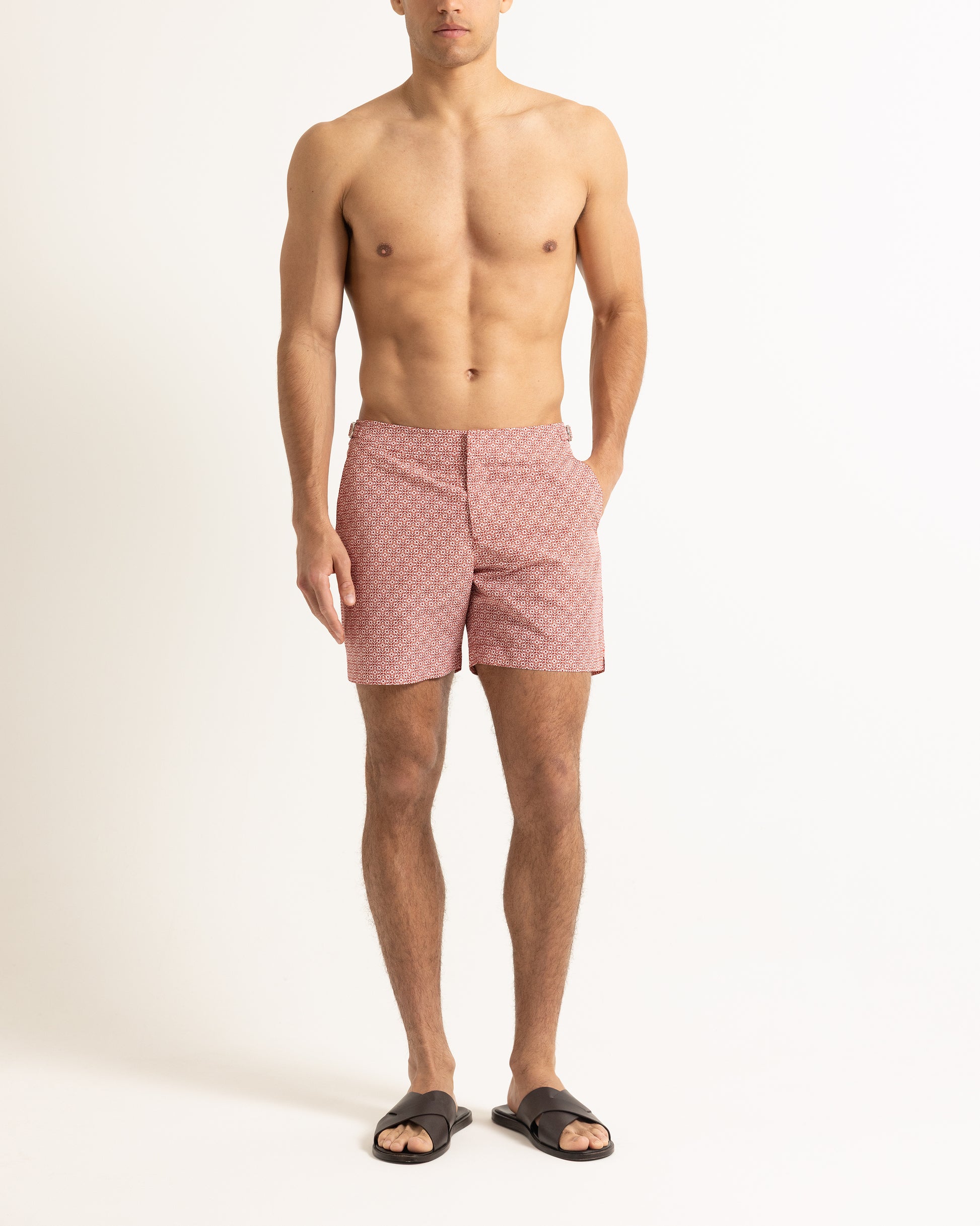 Man wearing red printed swim shorts on a plain background