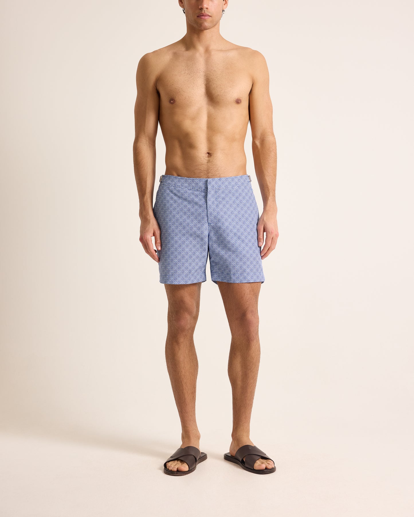Man wearing blue patterned swim shorts on a beige background