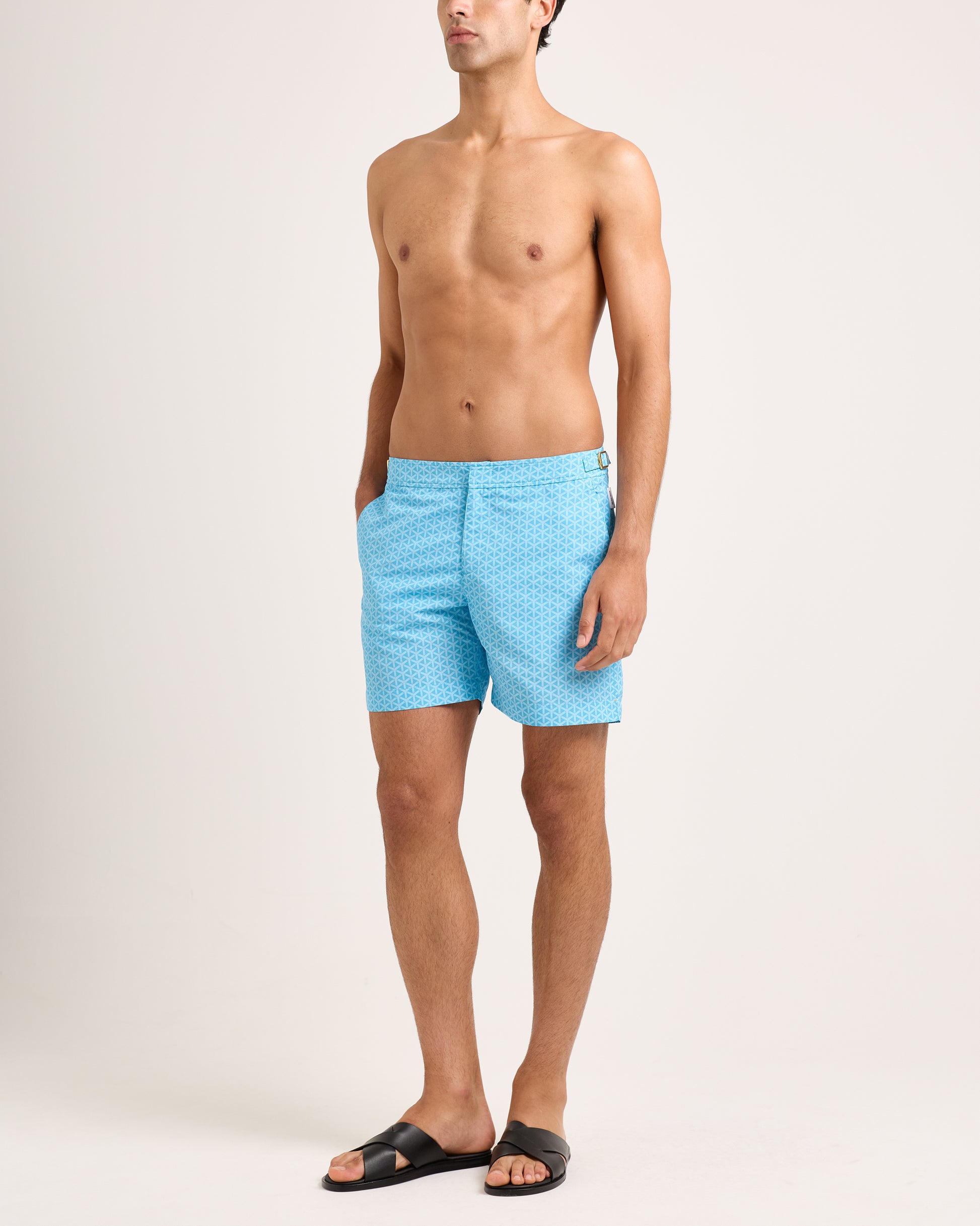 Man wearing light blue swim shorts with a subtle pattern on a white background