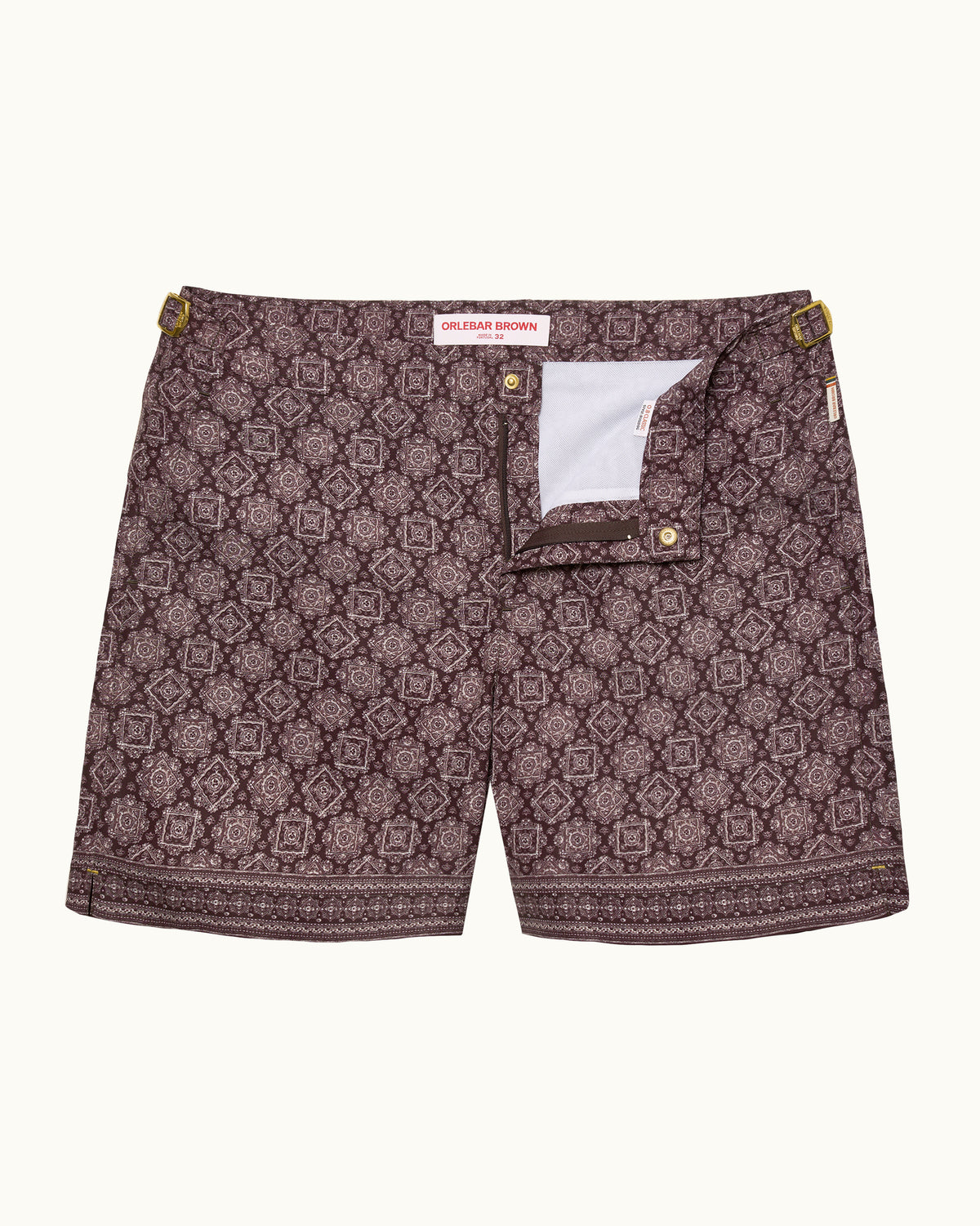 A pair of men's shorts featuring an all-over geometric medallion pattern in dark brown and muted purple, with a white inner lining visible at the fly opening.