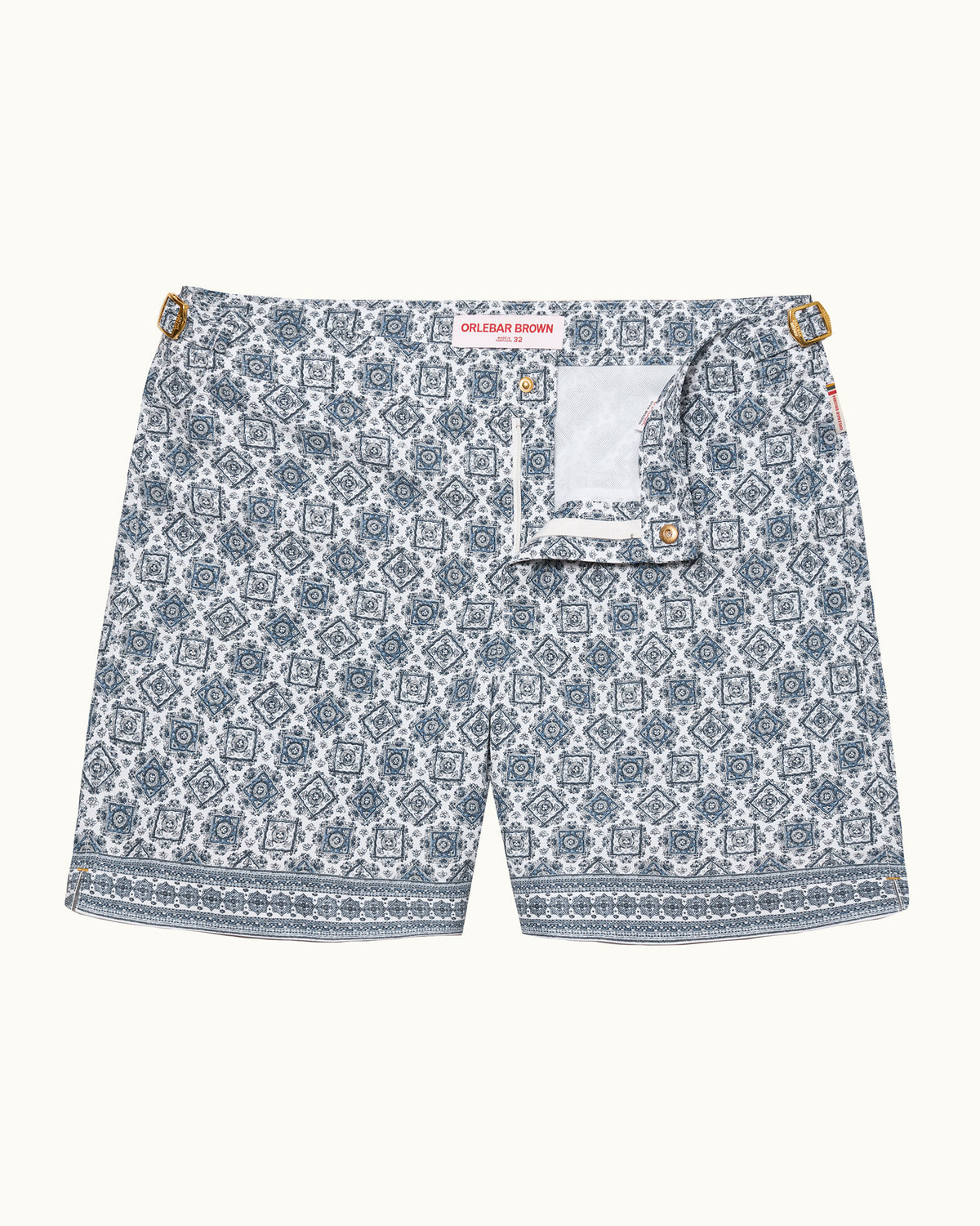 A pair of men's shorts featuring an all-over blue and white geometric mandala pattern, a white inner pocket with gold-tone snap buttons, and a red brand label at the waistband.