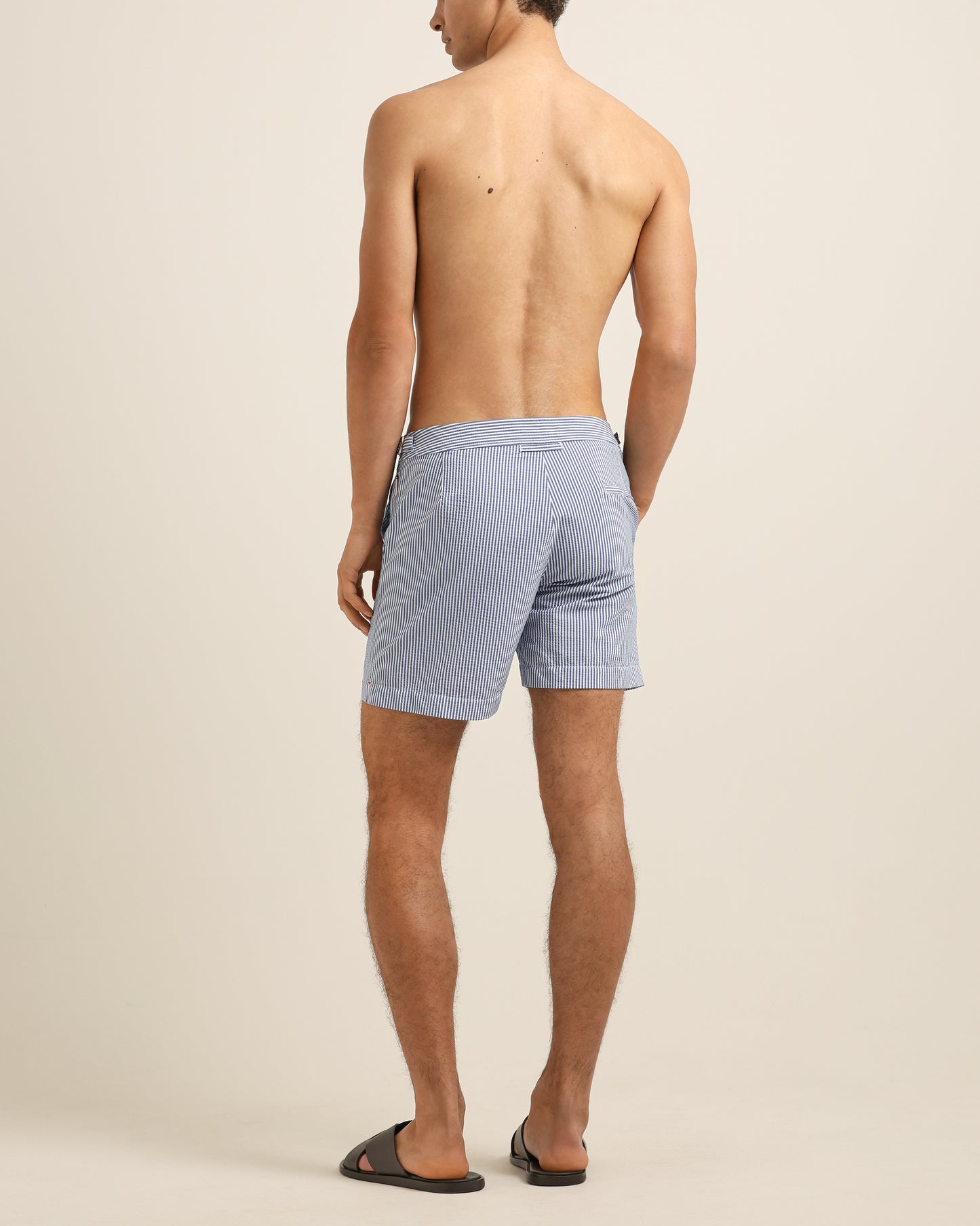 Man wearing light blue shorts on a beige background