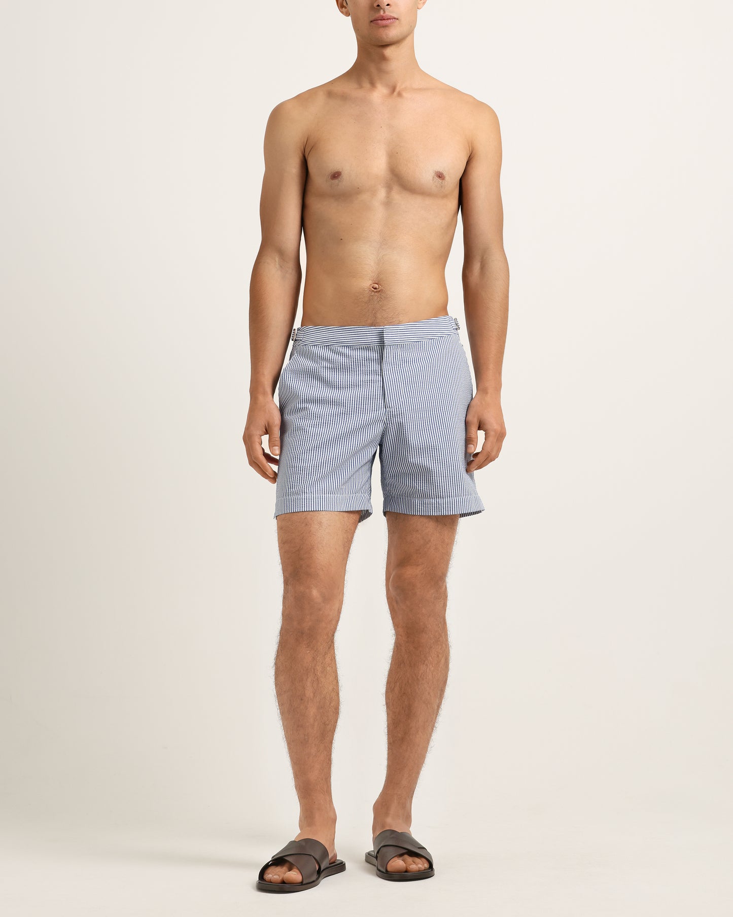 Man wearing light blue shorts on a plain background