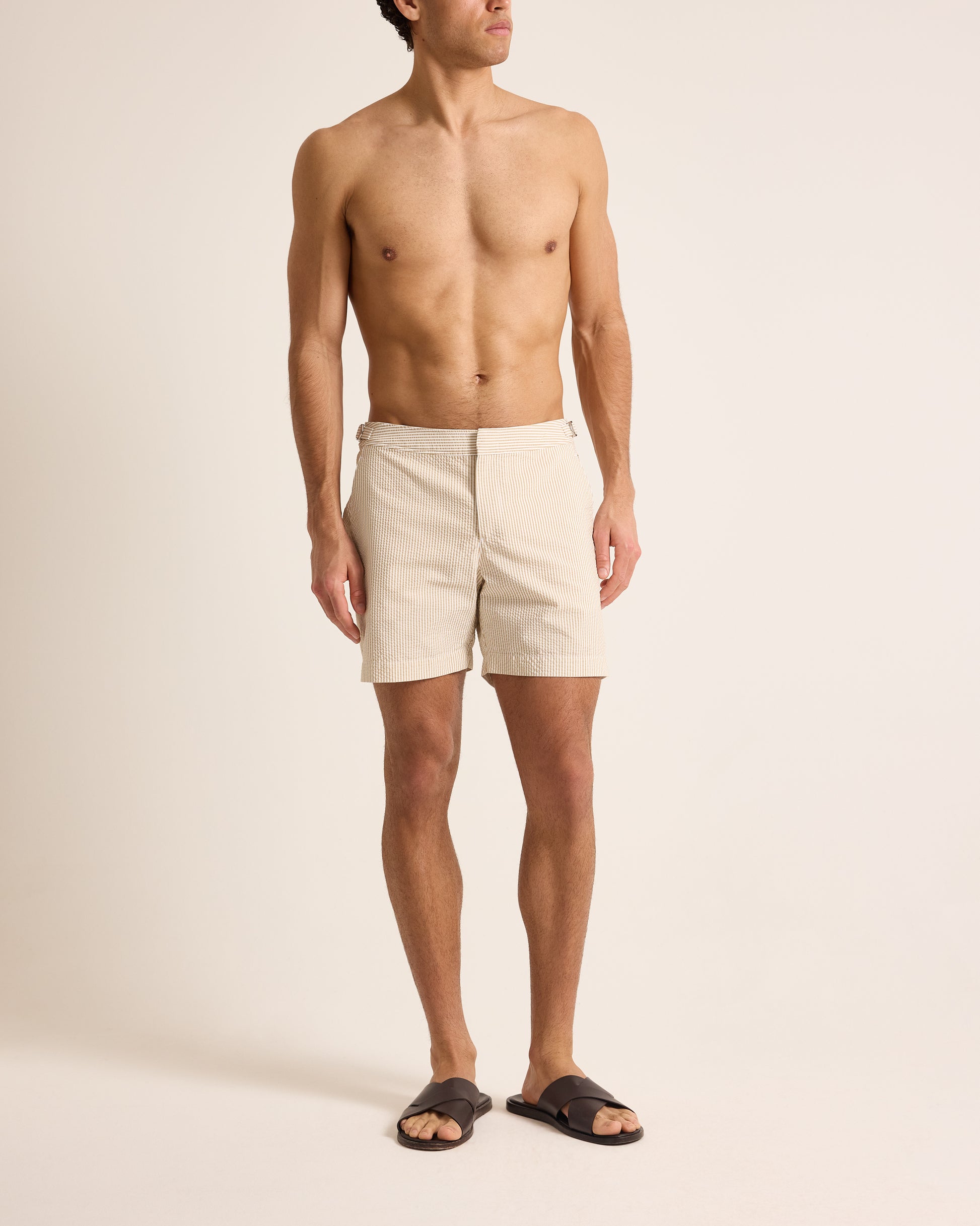 Man wearing beige shorts on a plain background
