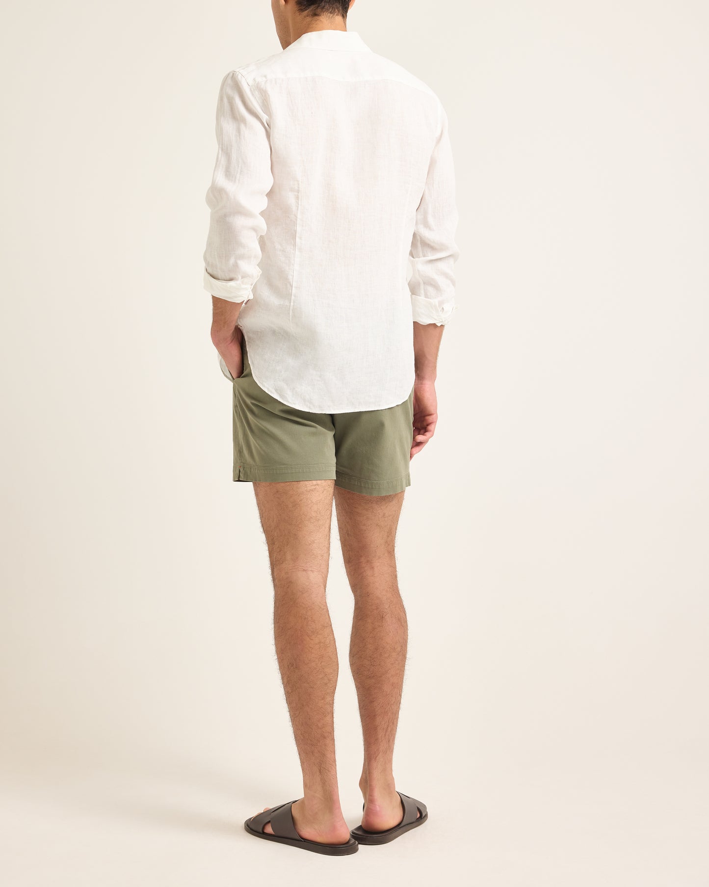 Person wearing a white shirt and green shorts on a plain background