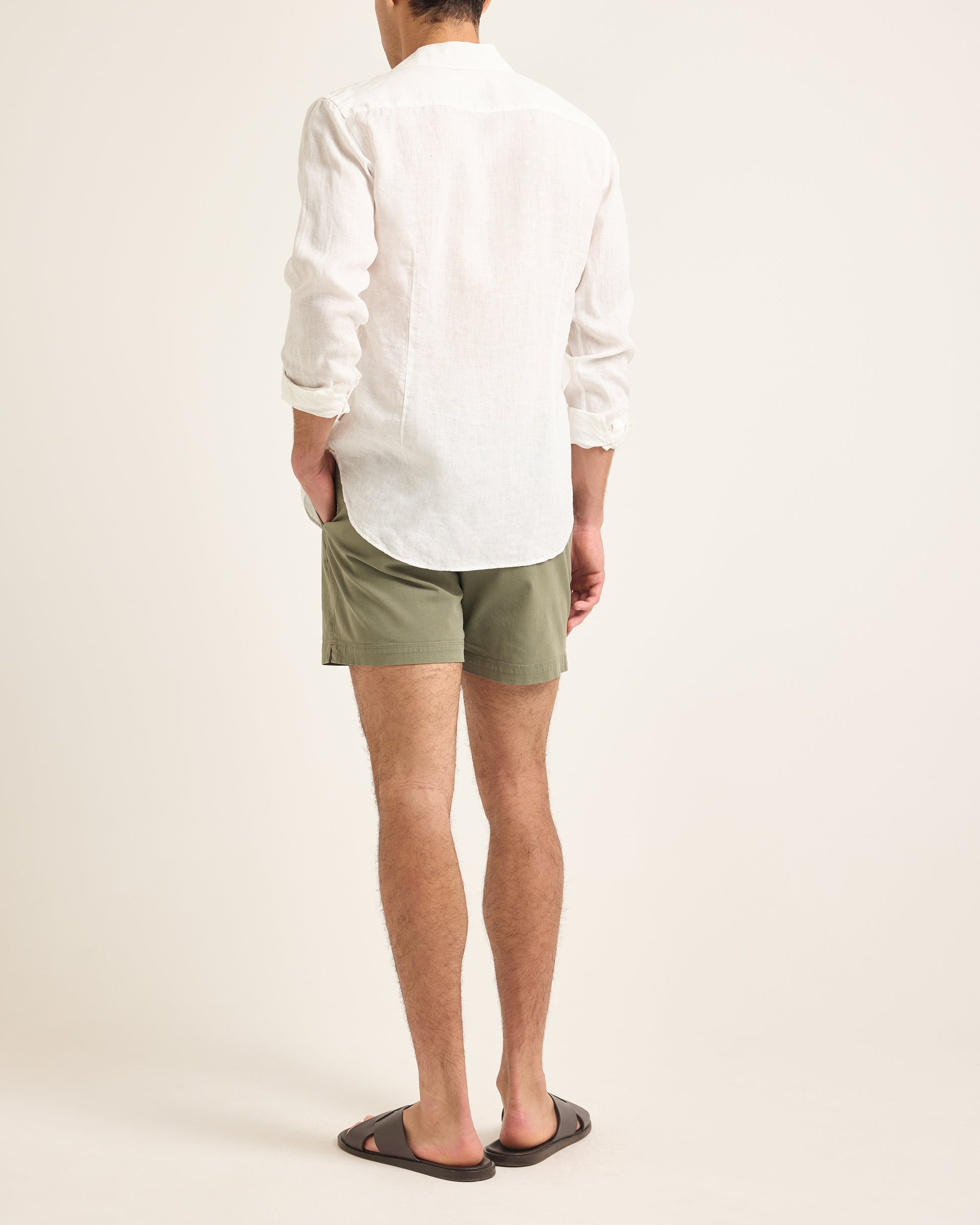 Person wearing a white shirt and green shorts on a plain background