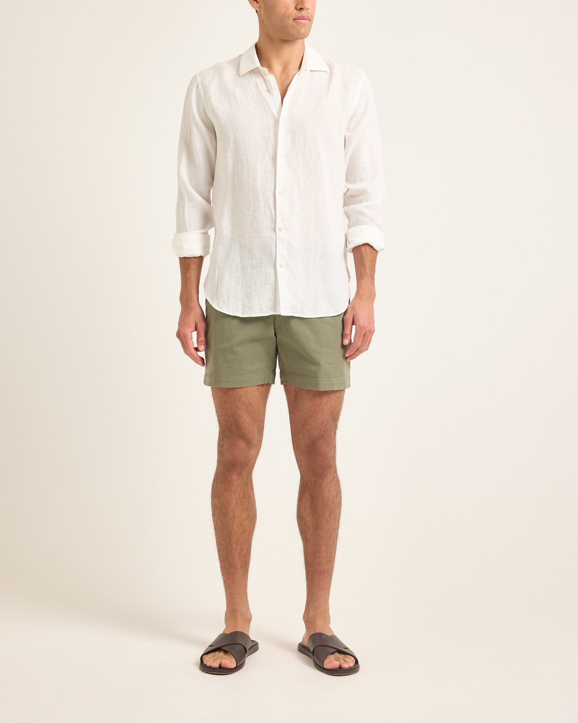 Person wearing a white shirt and green shorts on a plain background