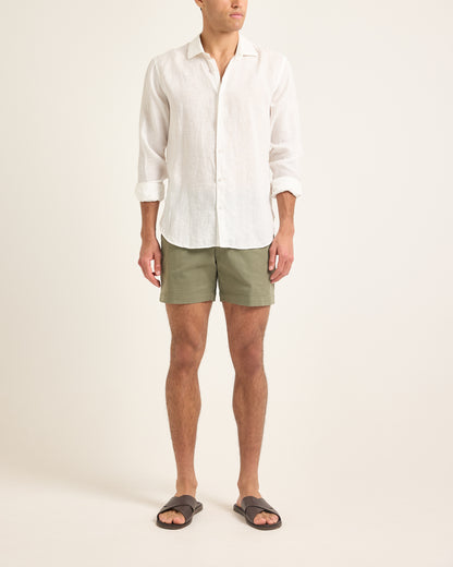 Person wearing a white shirt and green shorts on a plain background