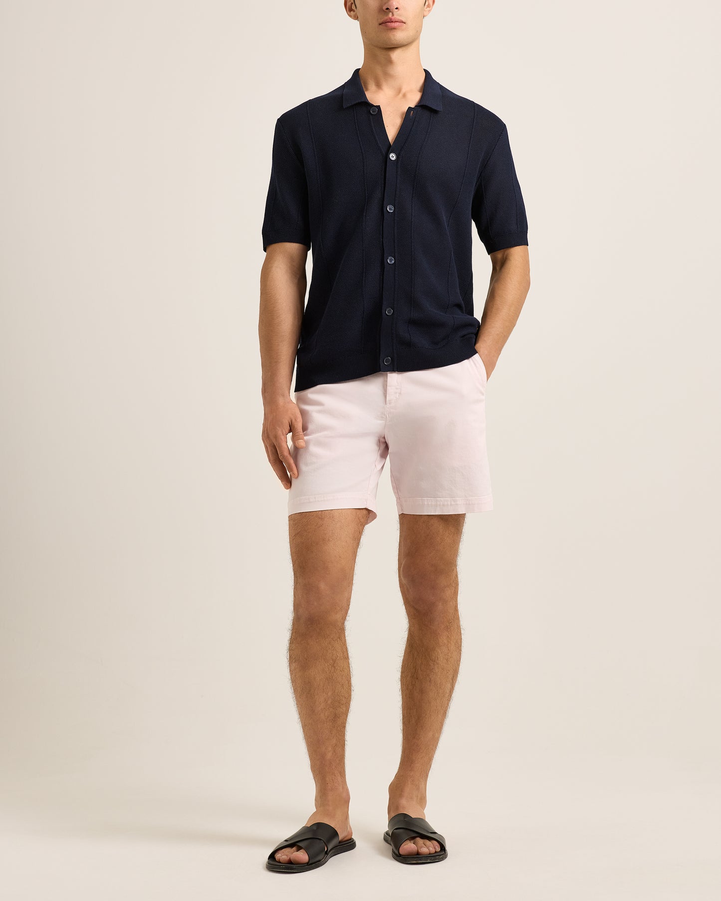Man wearing a navy shirt and pink shorts on a beige background