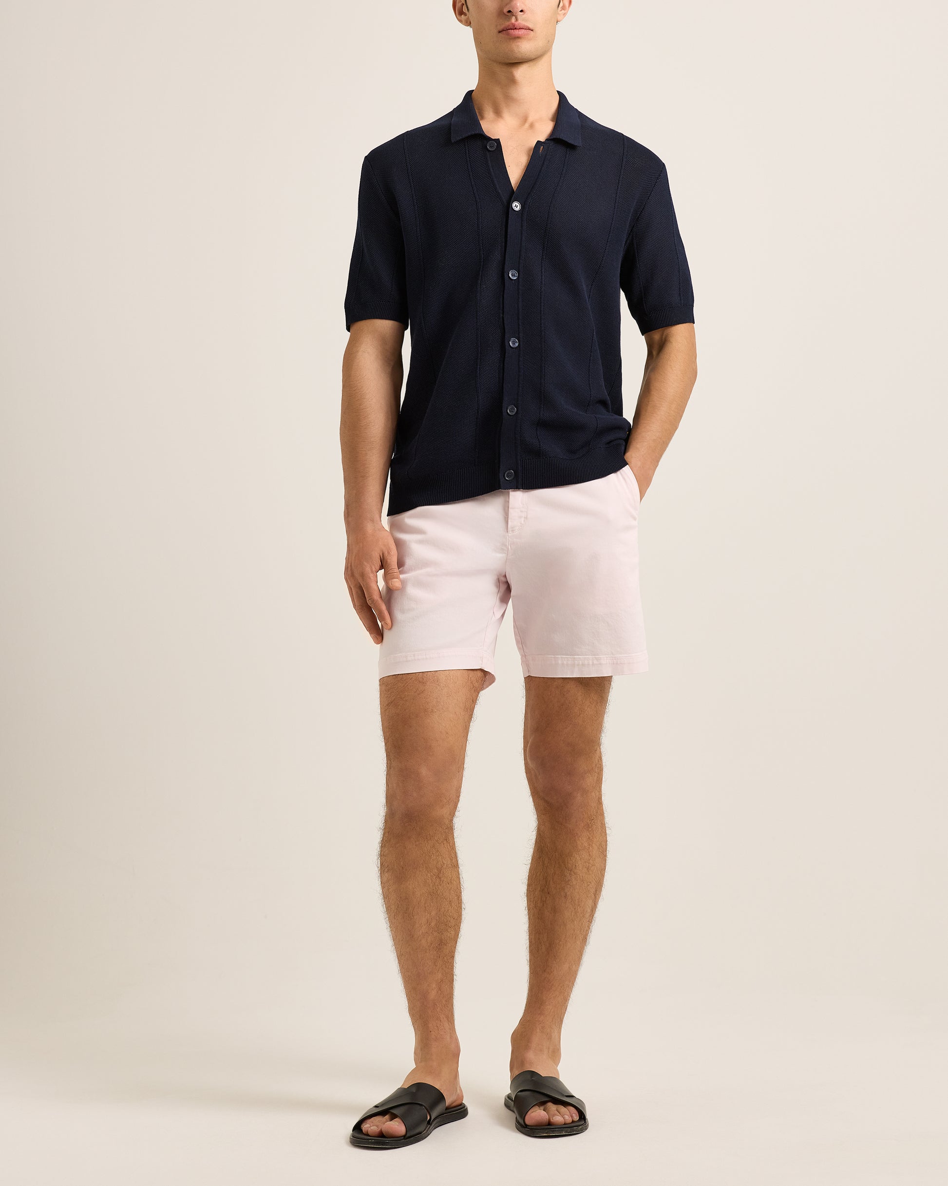 Man wearing a navy shirt and pink shorts on a beige background