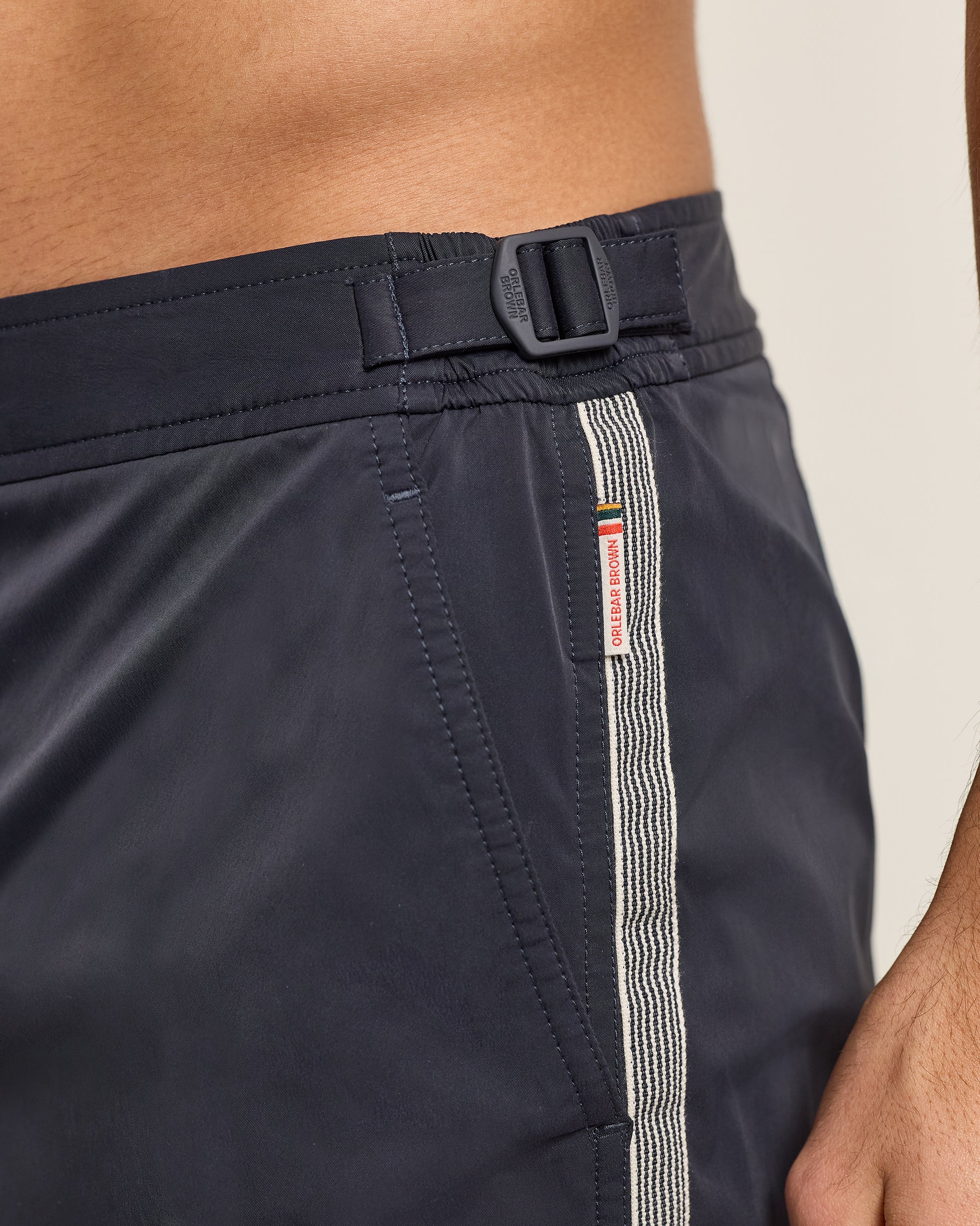 Navy shorts with a belt and white stripe on a neutral background