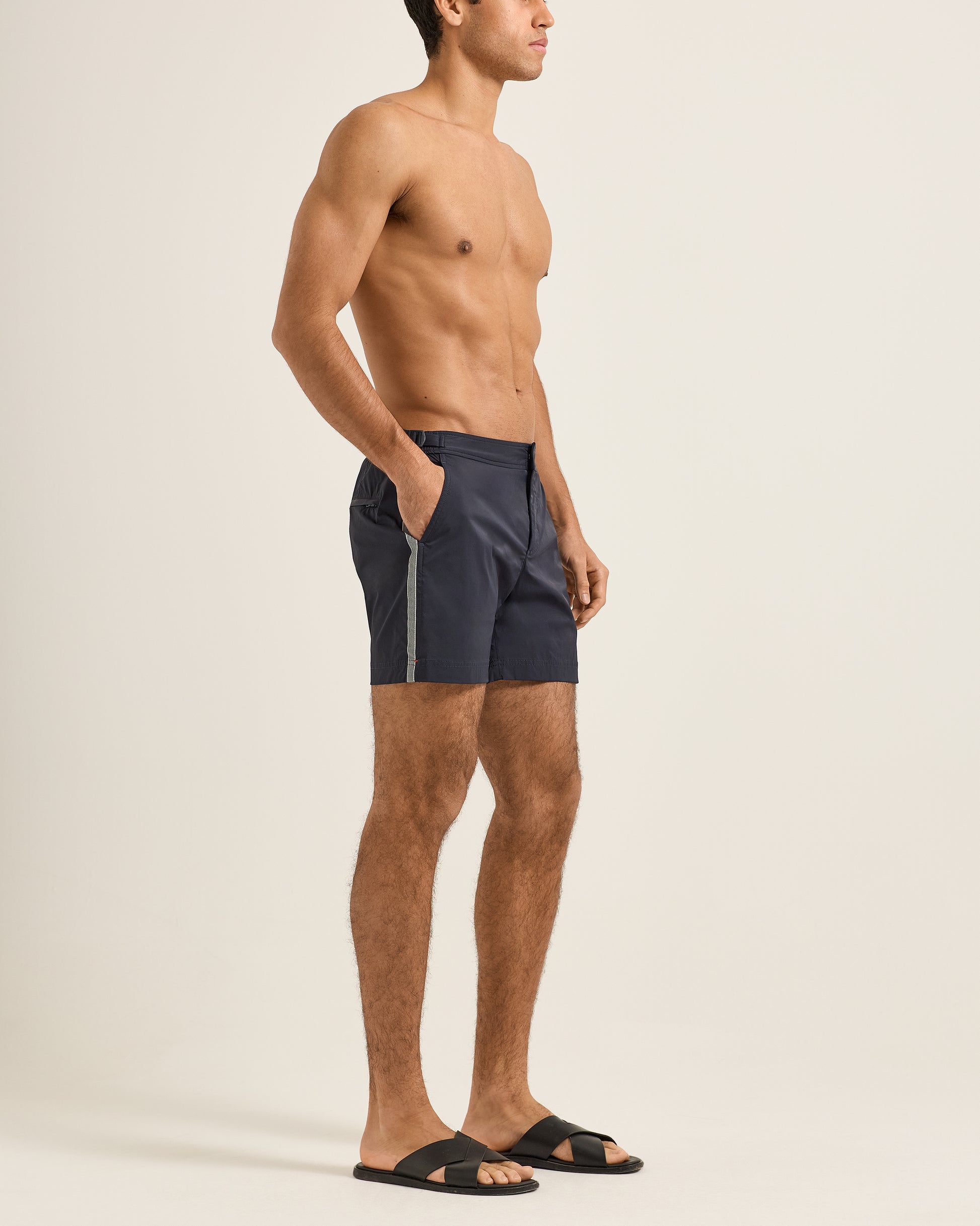 Man wearing navy swim shorts on a beige background