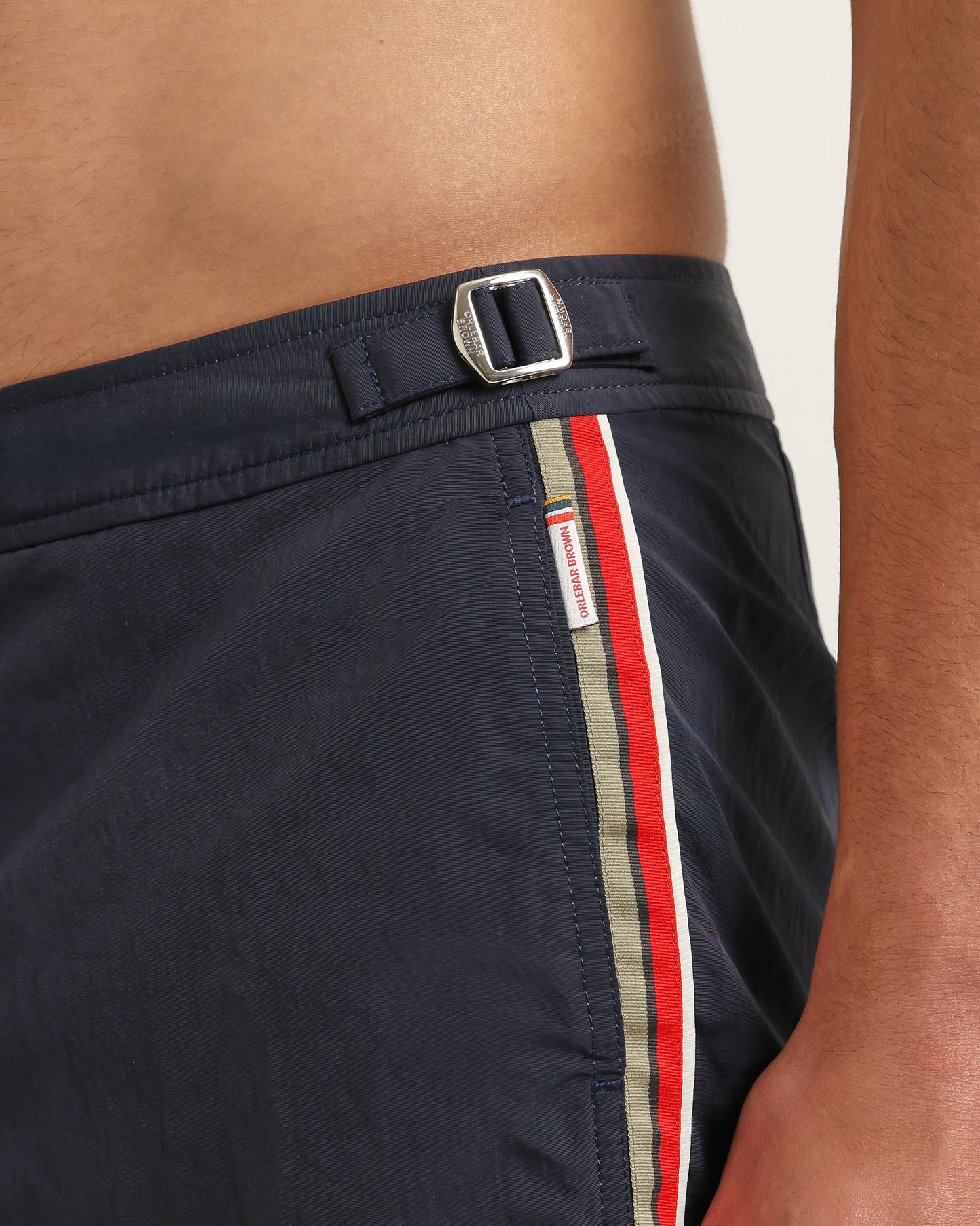 Navy swim shorts with a striped side panel and brand logo on a neutral background