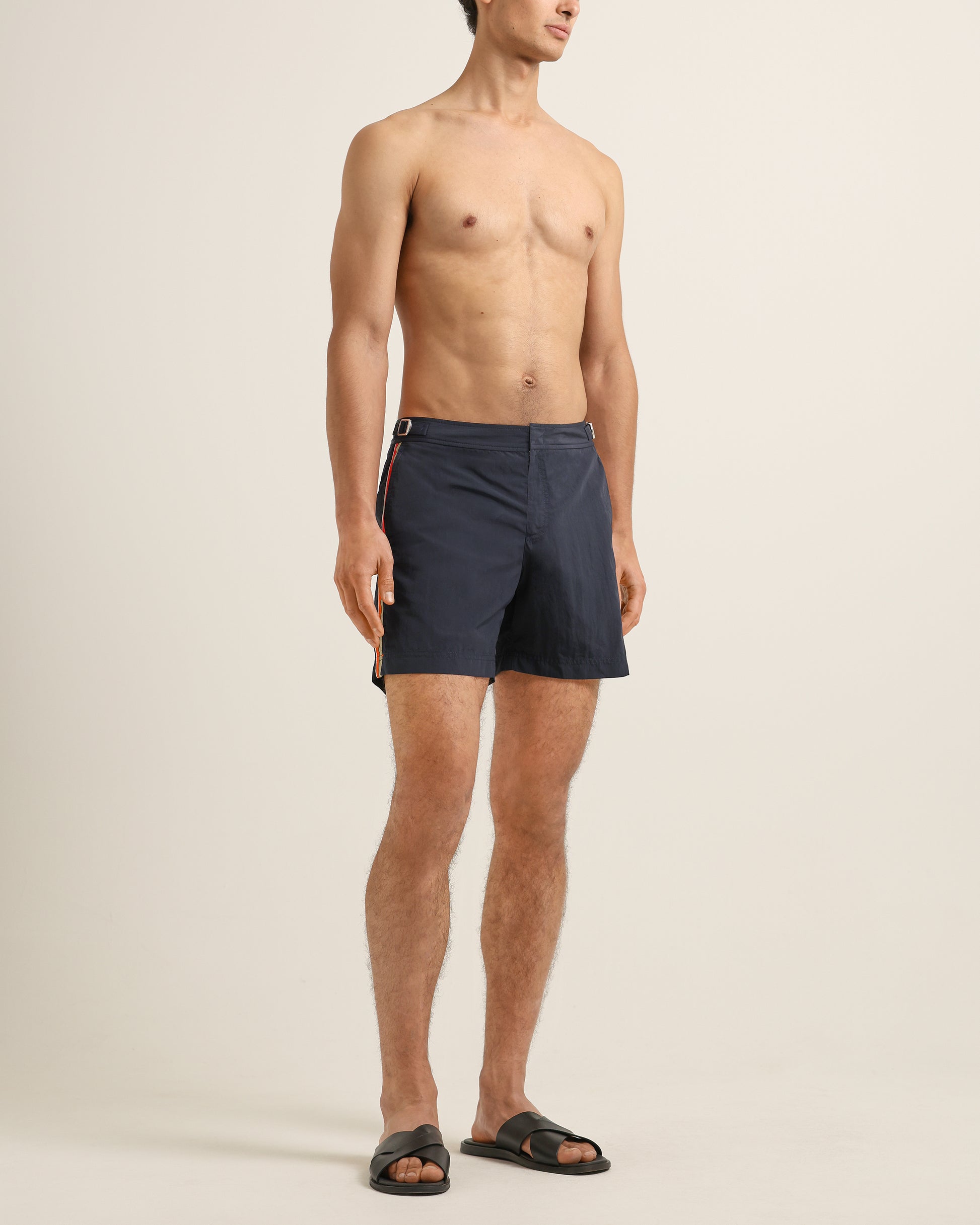 Man wearing navy blue swim shorts on a beige background