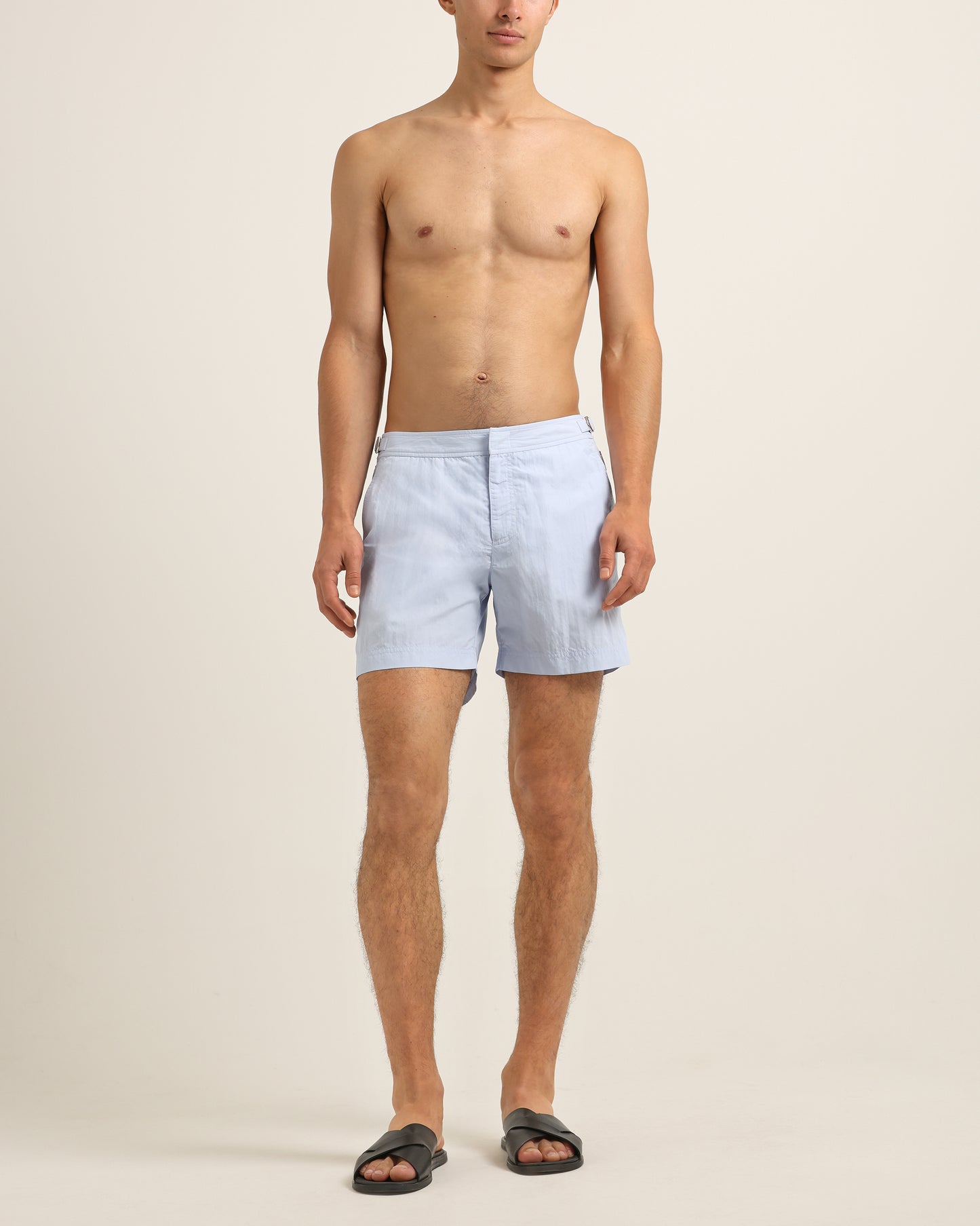 Man wearing light blue shorts on a beige background