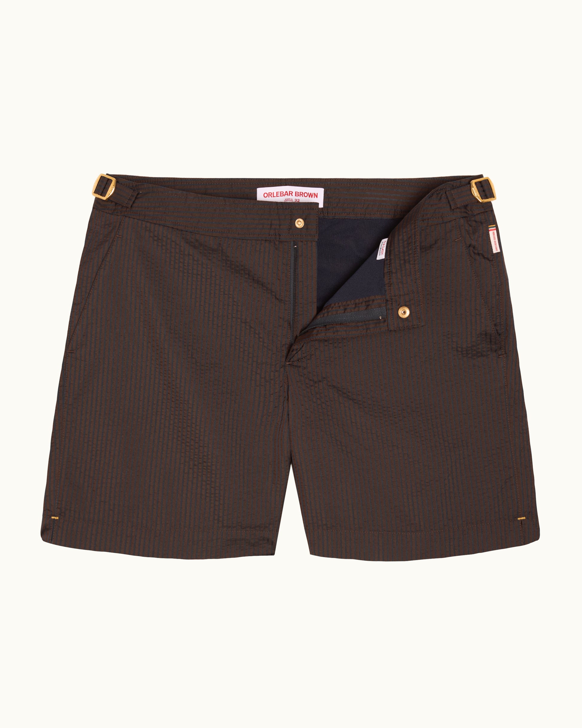 A pair of dark brown pinstriped shorts with gold-tone metal hardware, shown flat against a light off-white background