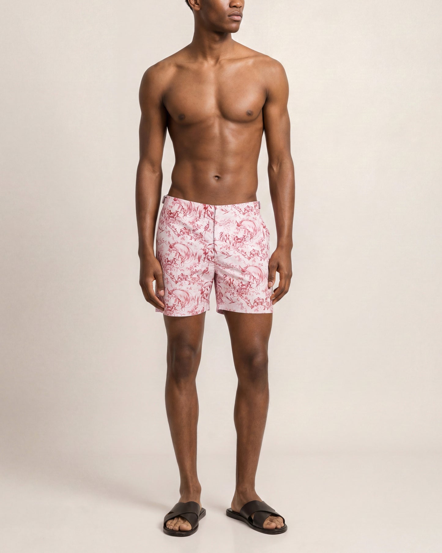 Man wearing pink floral swim shorts on a beige background