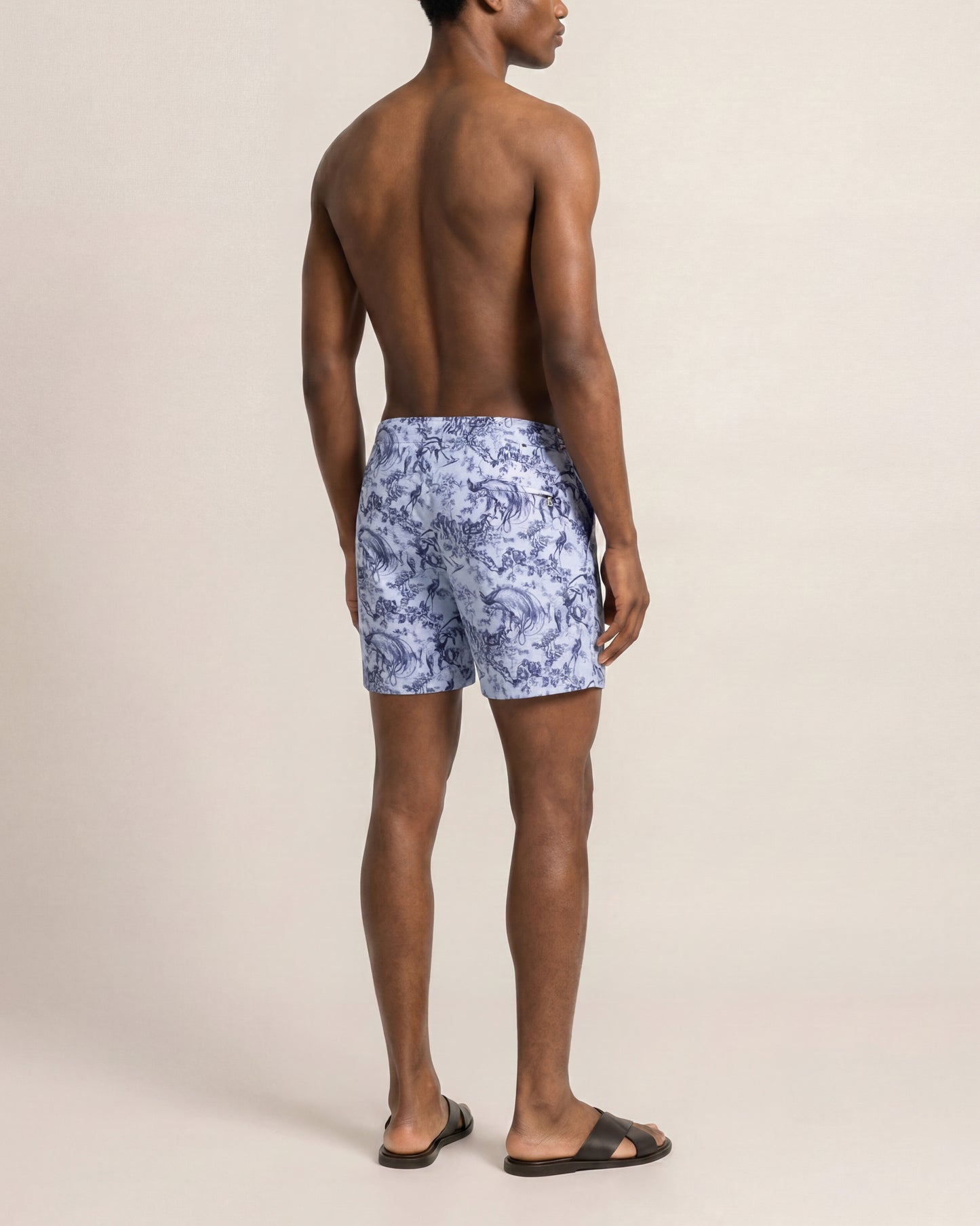 Man wearing blue floral swim shorts on a beige background