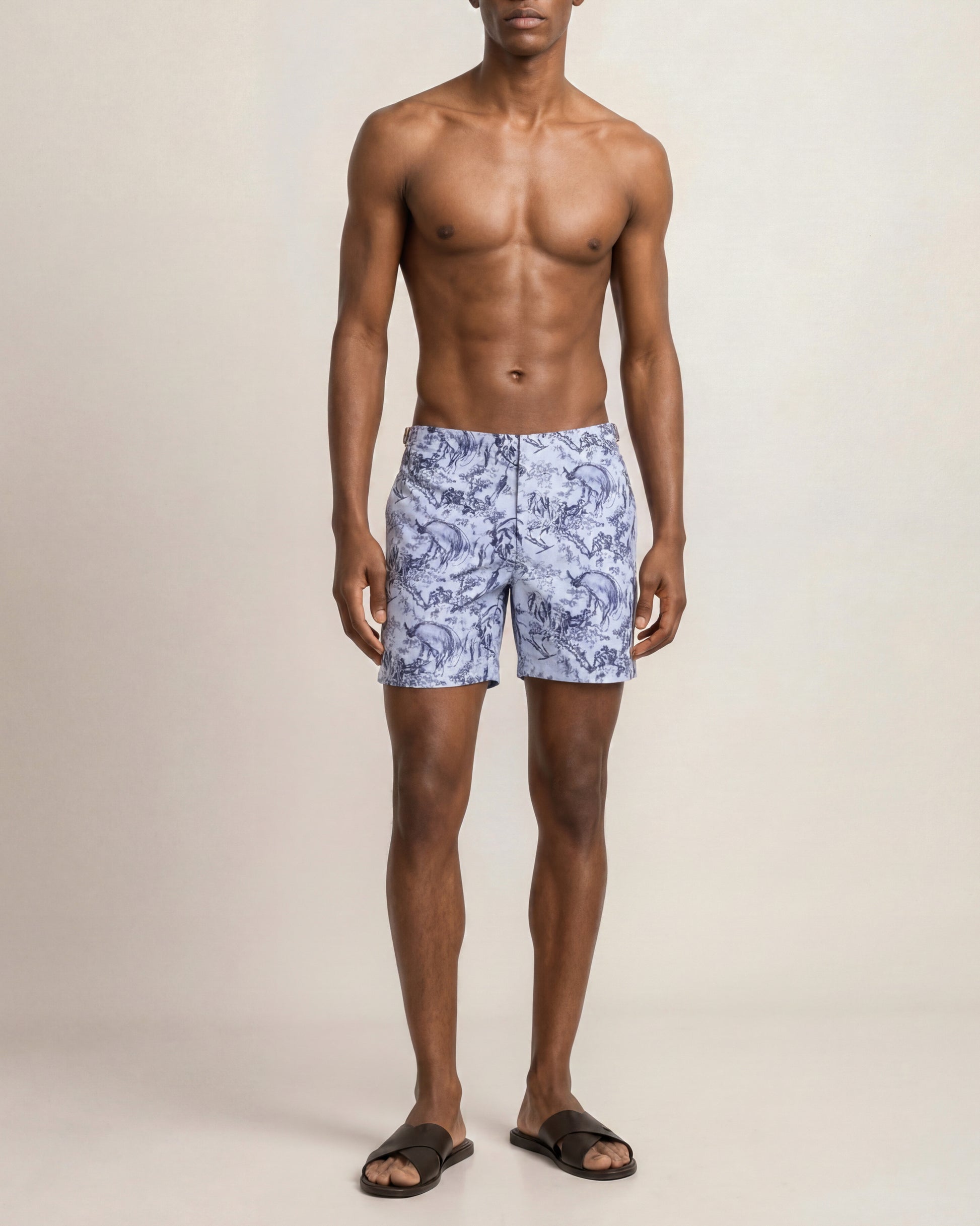 Man wearing blue patterned swim shorts on a beige background
