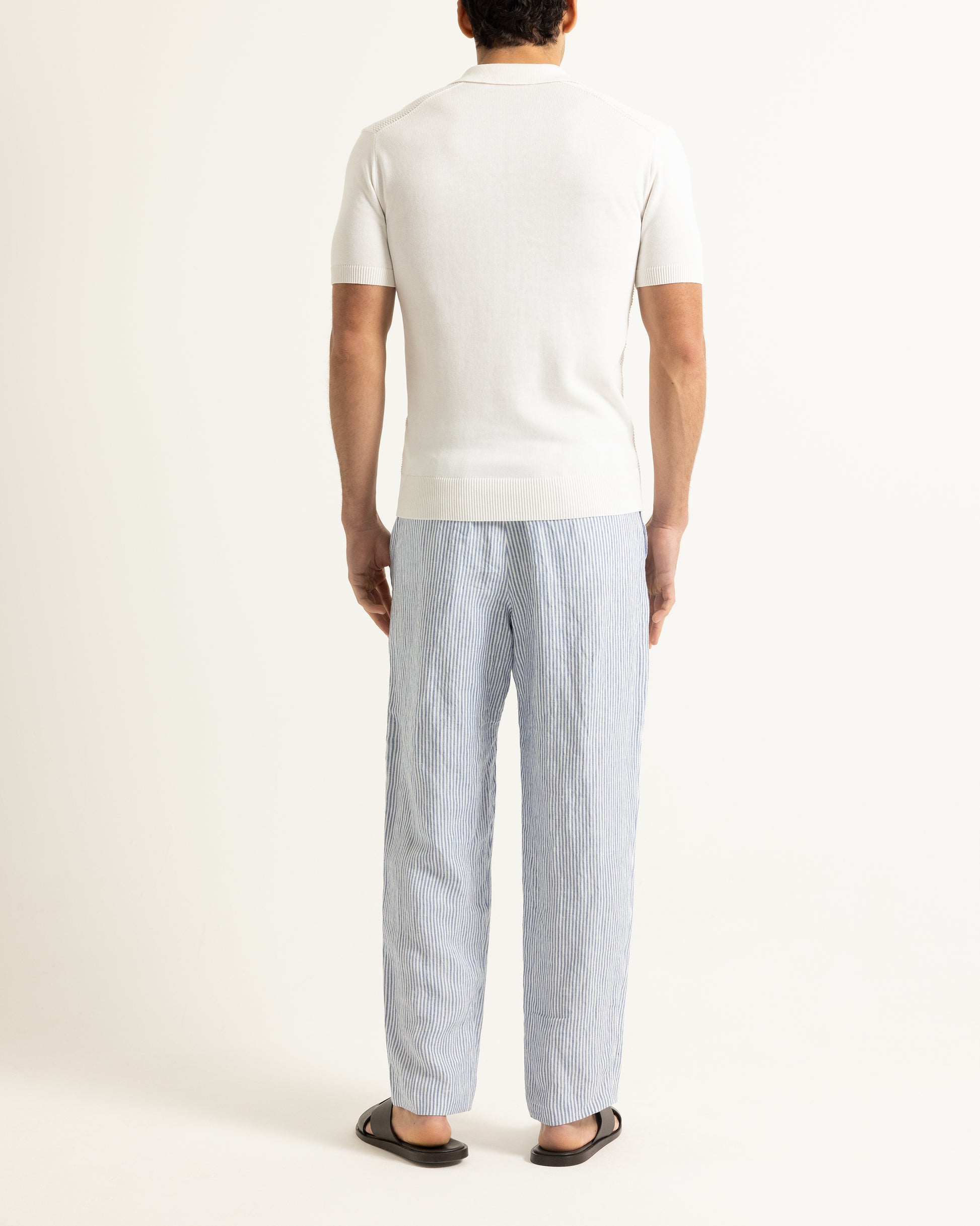 Person wearing a white t-shirt and light blue striped pants on a plain background