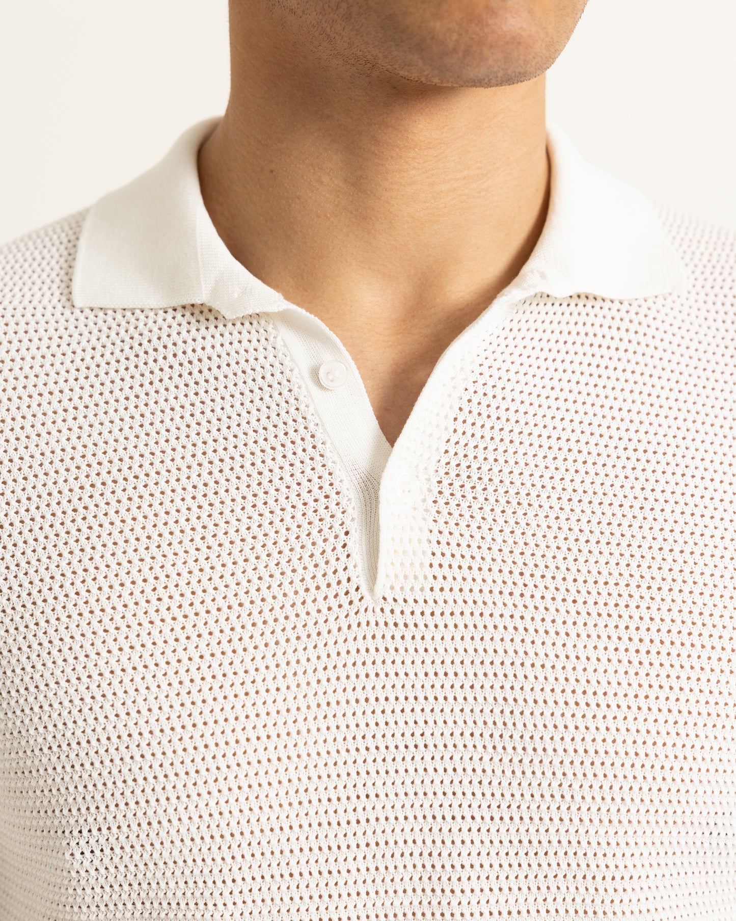 Close-up of a person wearing a textured white shirt with a collar.