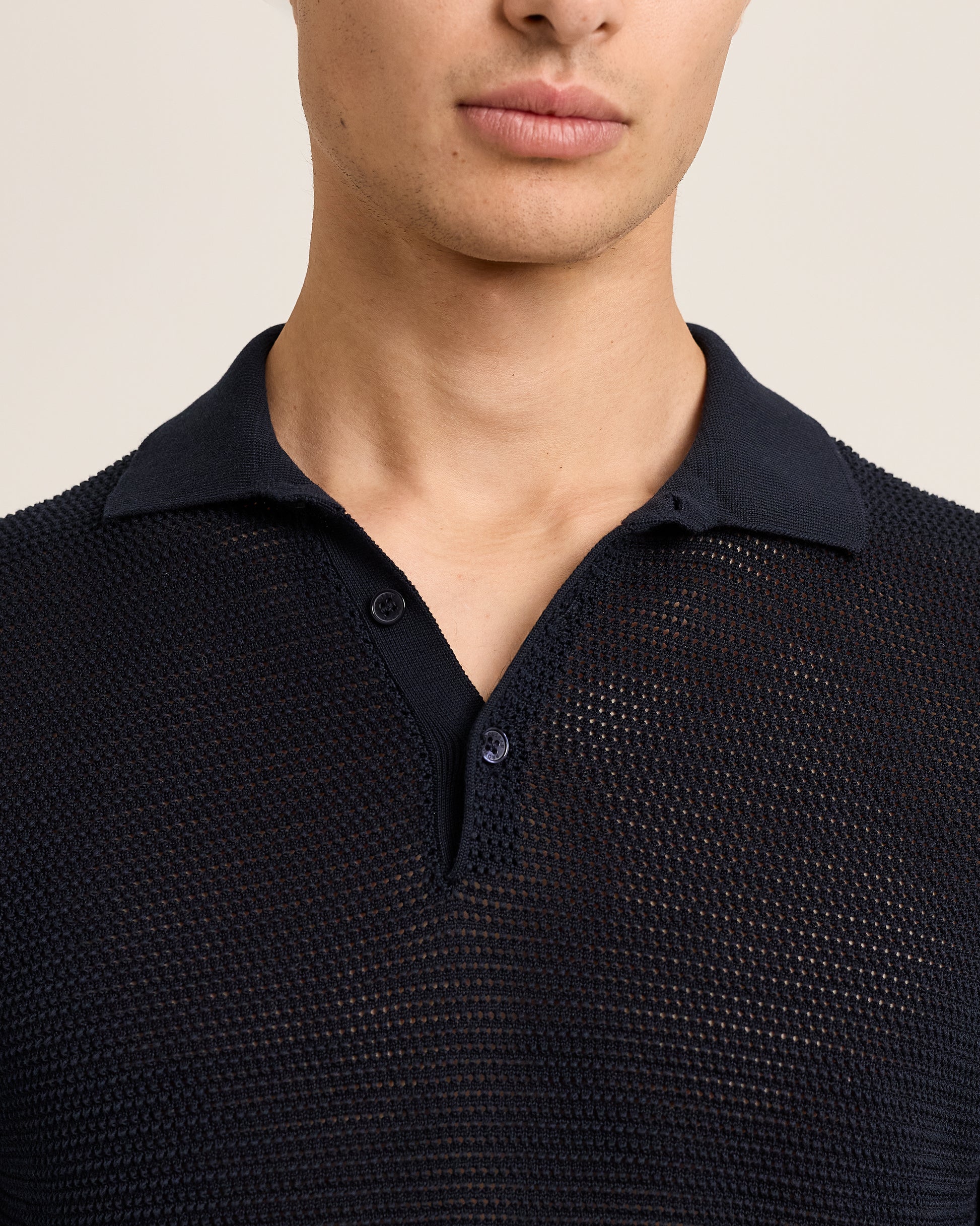 Navy textured polo shirt worn by a person on a beige background