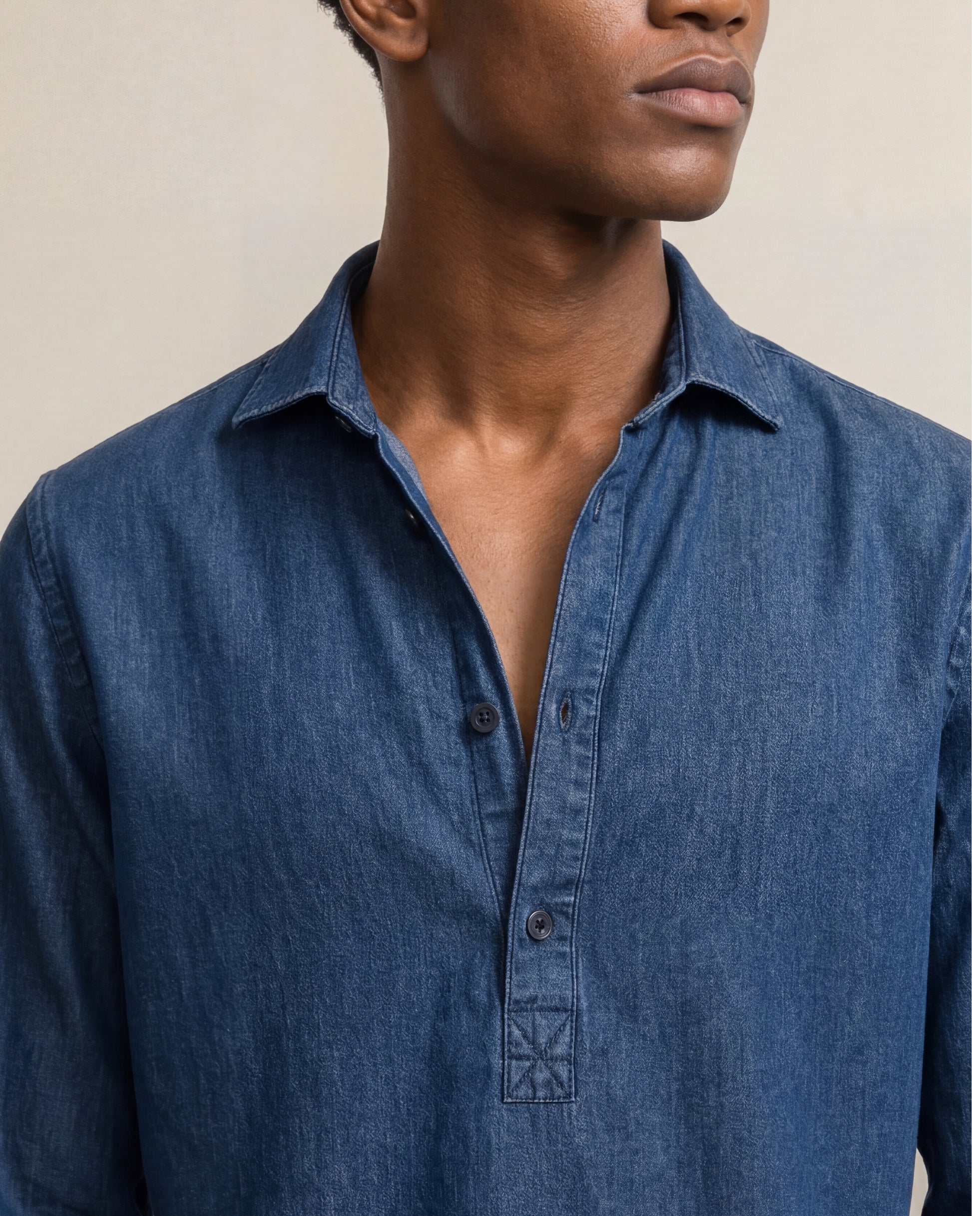 Man wearing a blue denim shirt against a neutral background