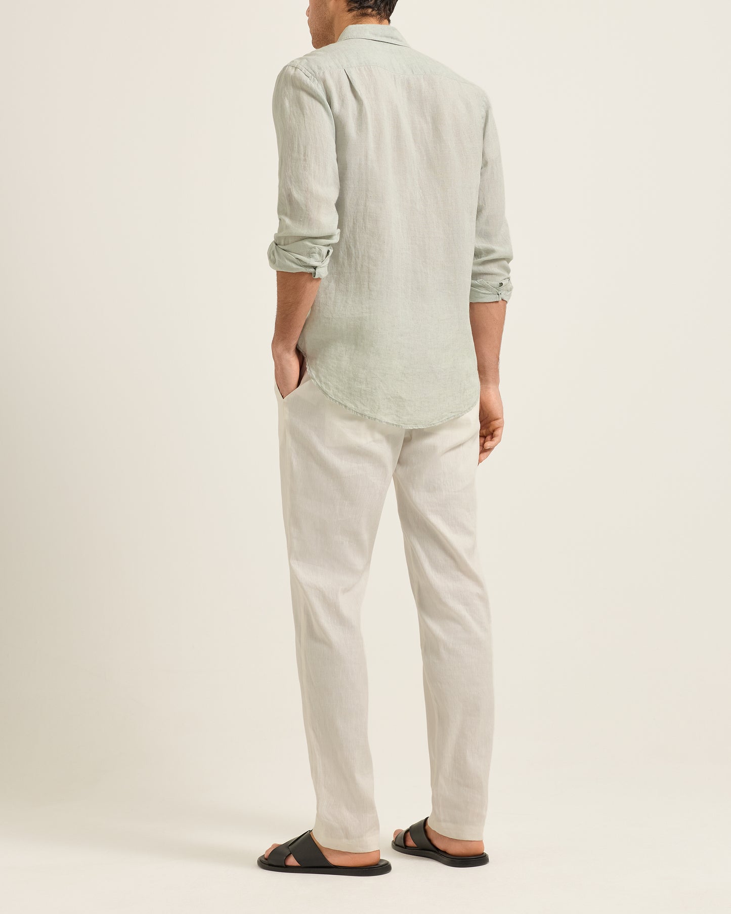 Person wearing a light green shirt and beige pants on a white background