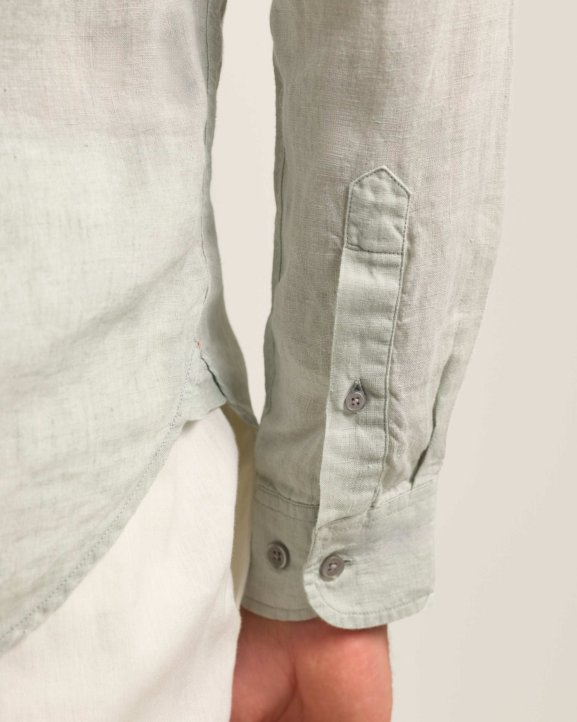 Light green shirt with rolled-up sleeves on a plain background