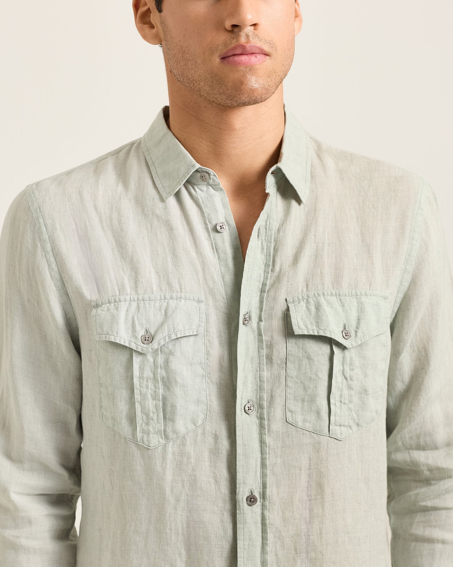 Light gray button-up shirt worn by a person on a plain background